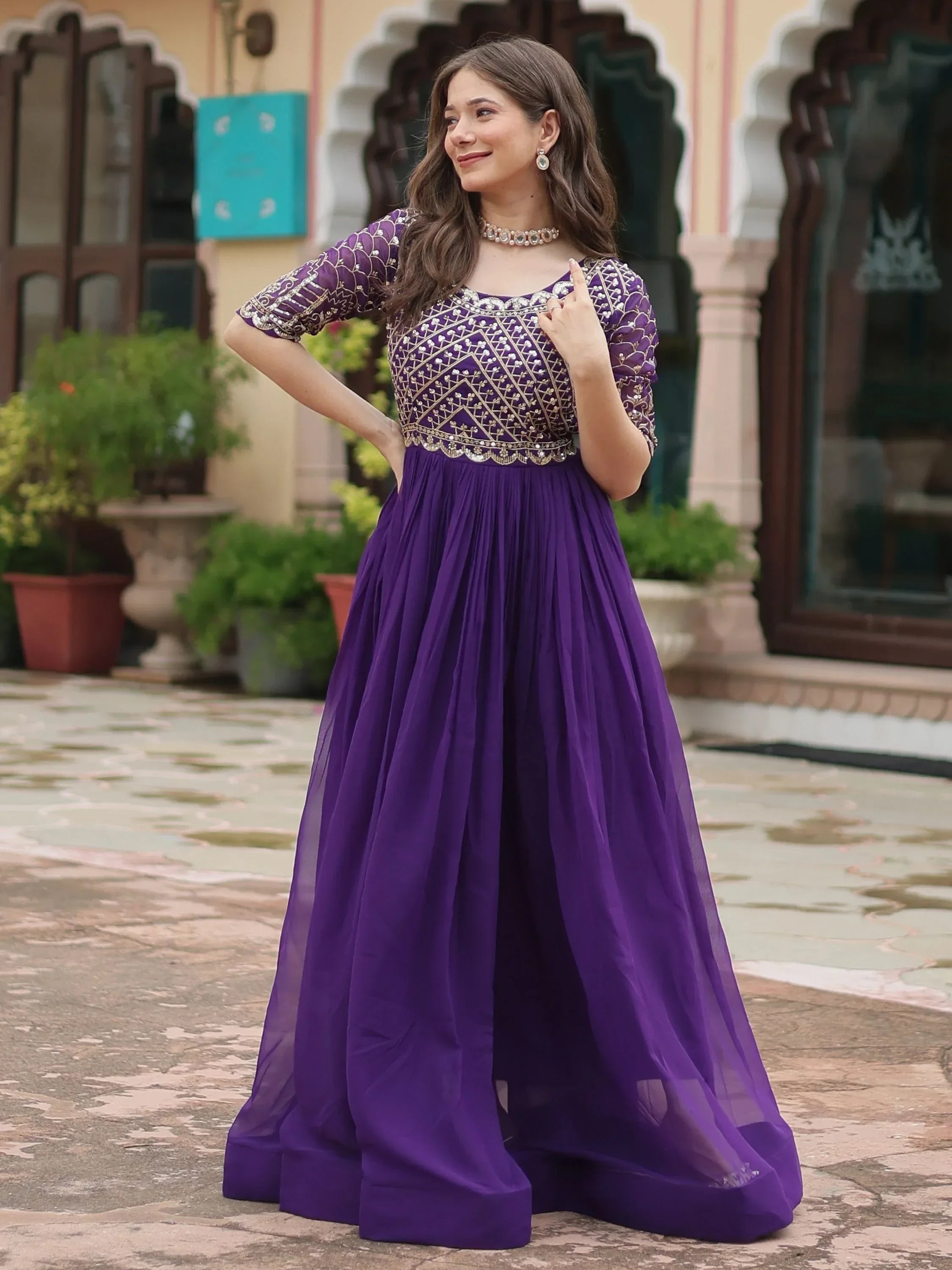 Woman wearing a purple embroidered ethnic gown with sheer skirt, standing outdoors