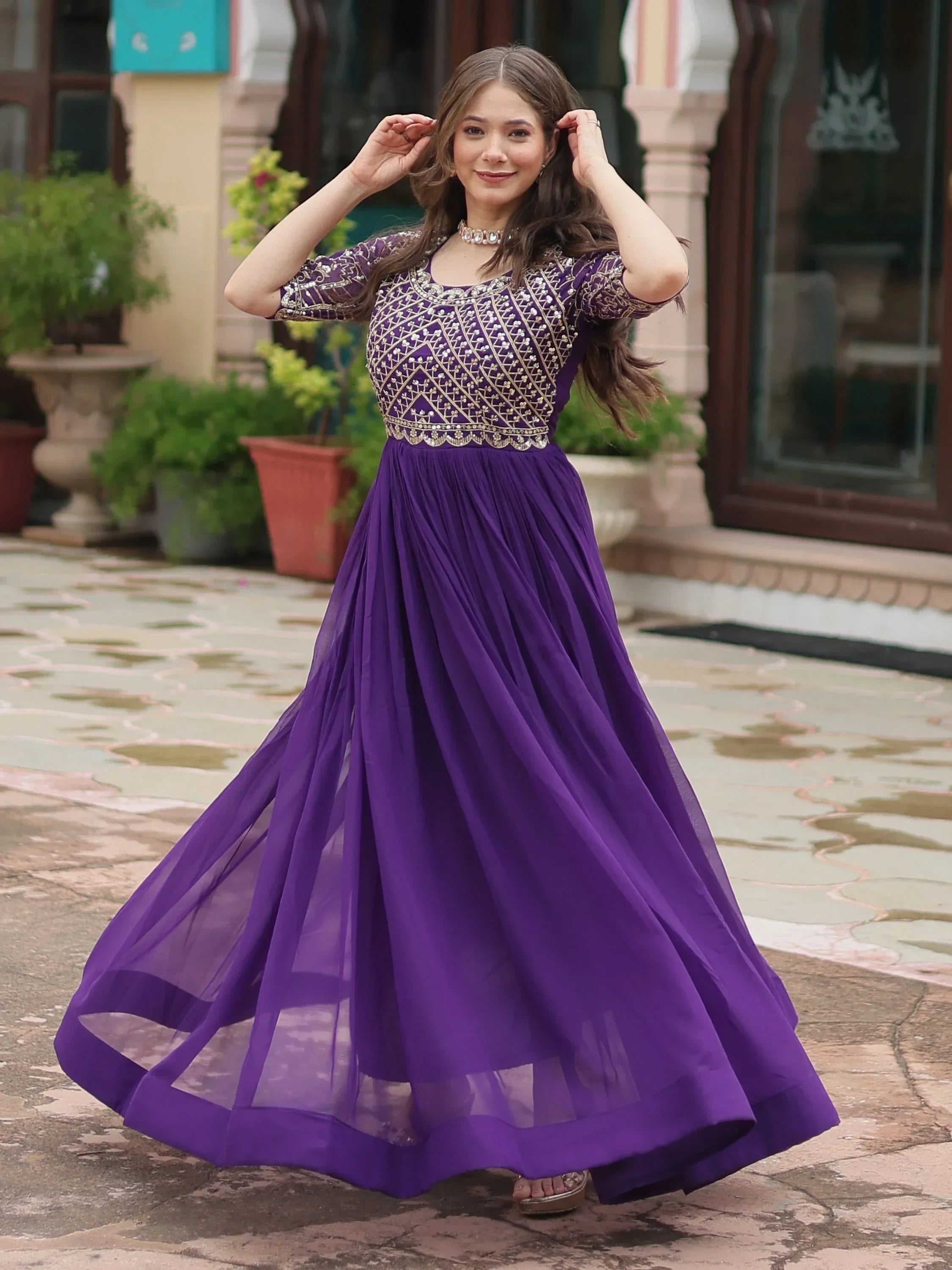 Woman in a purple embroidered ethnic gown with sheer skirt, posing outdoors
