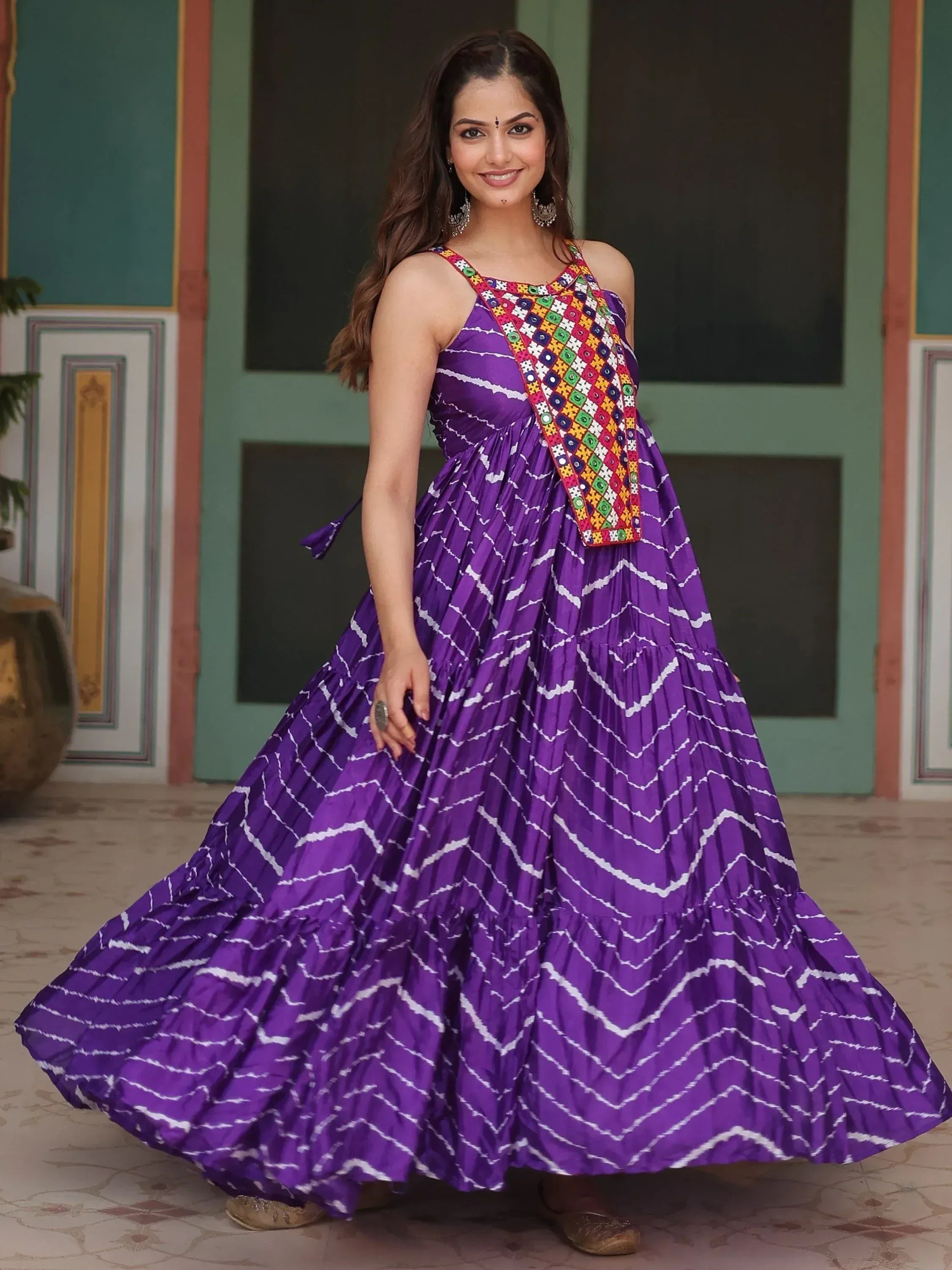 Purple ethnic gown with white zigzag print and colorful mirror work, perfect for Indian festive occasions.