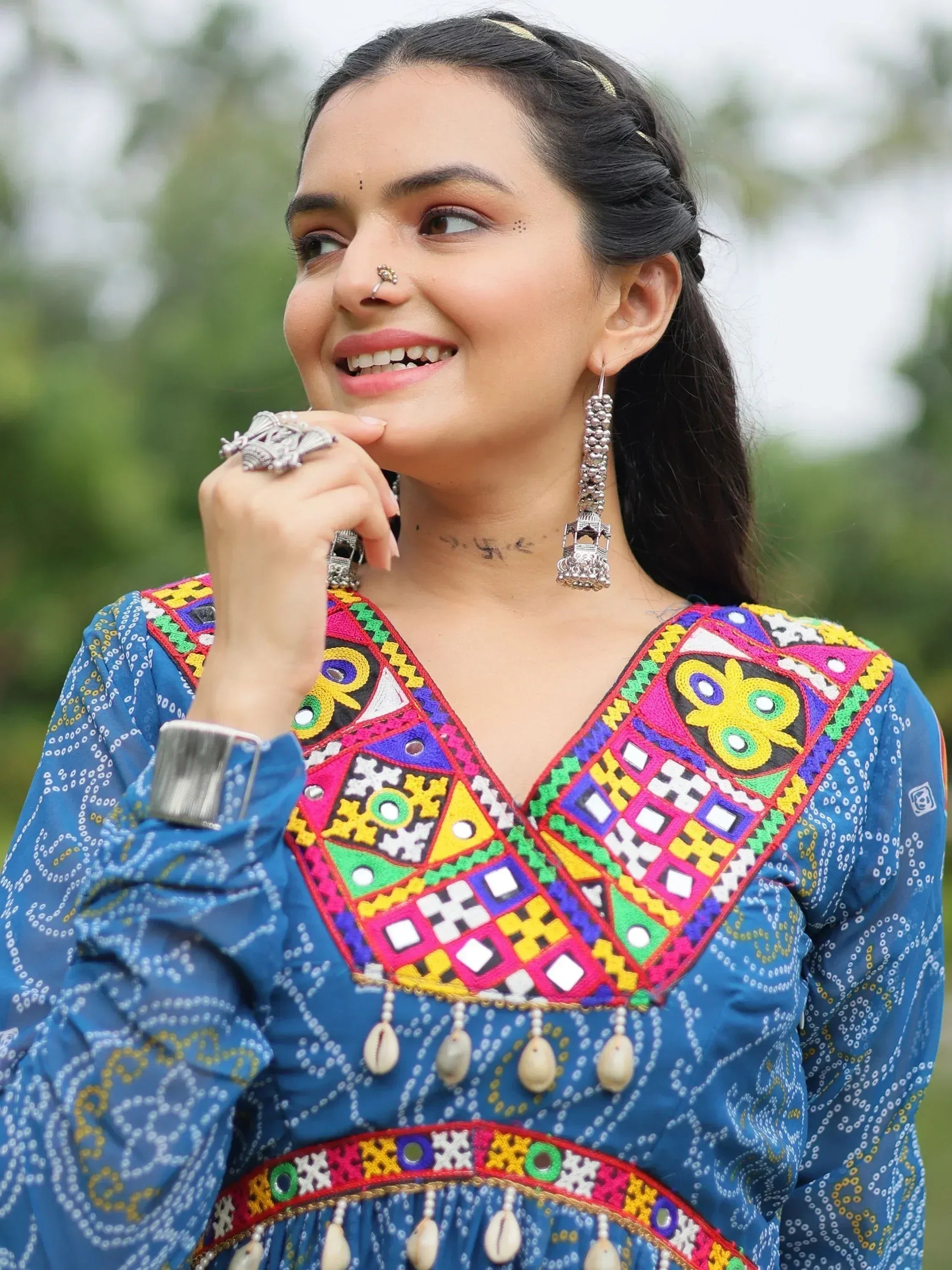 Vibrant blue ethnic kurti with colorful mirror work, embroidery, and shell tassels, paired with traditional silver jewelry.