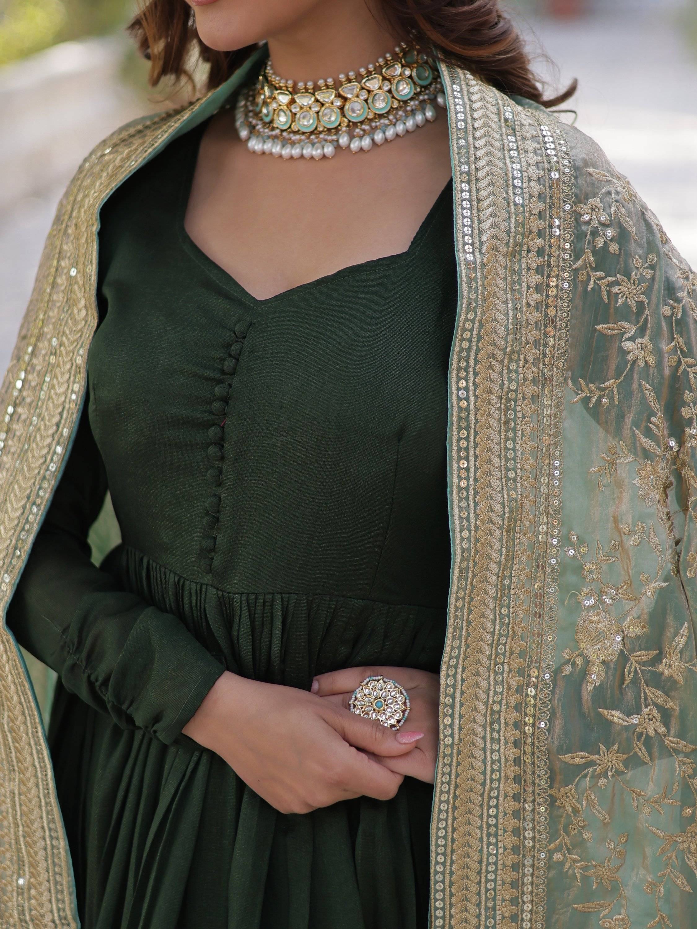 Woman in green ethnic gown with gold embroidered dupatta and traditional jewelry