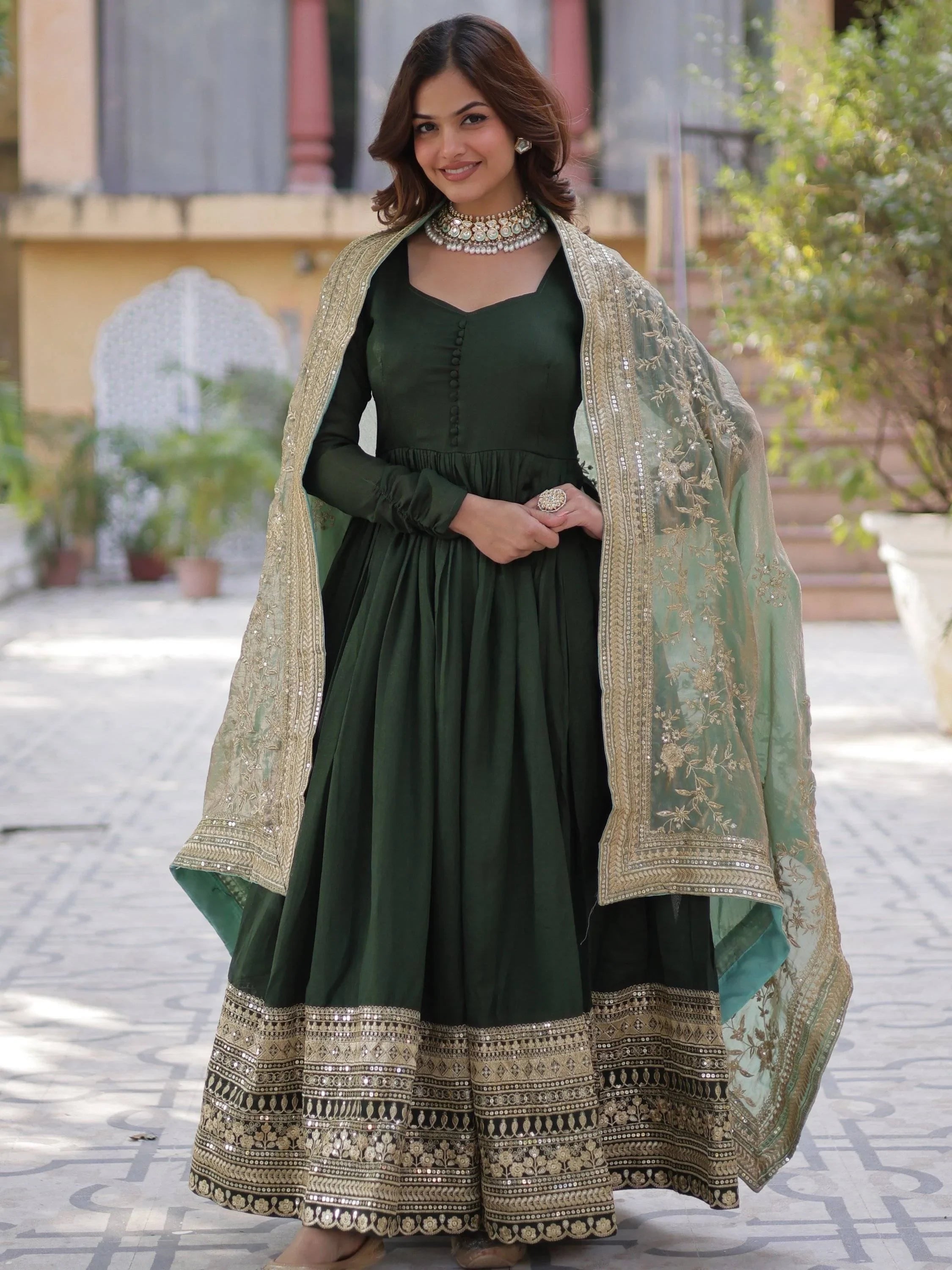 Woman wearing green ethnic gown with gold embroidery and matching dupatta outdoors
