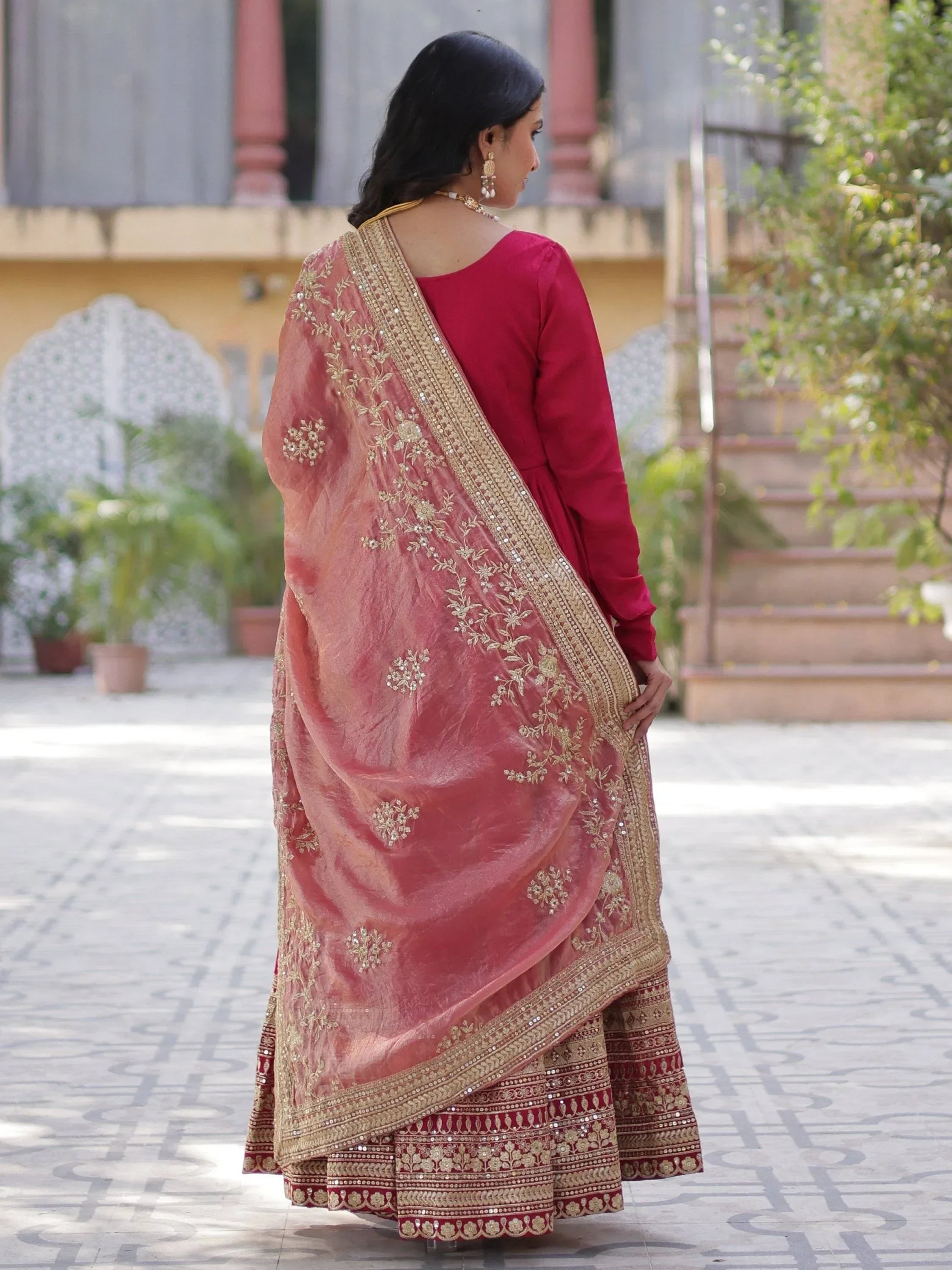 Woman wearing pink embroidered lehenga choli with dupatta, Indian ethnic outfit, outdoor setting