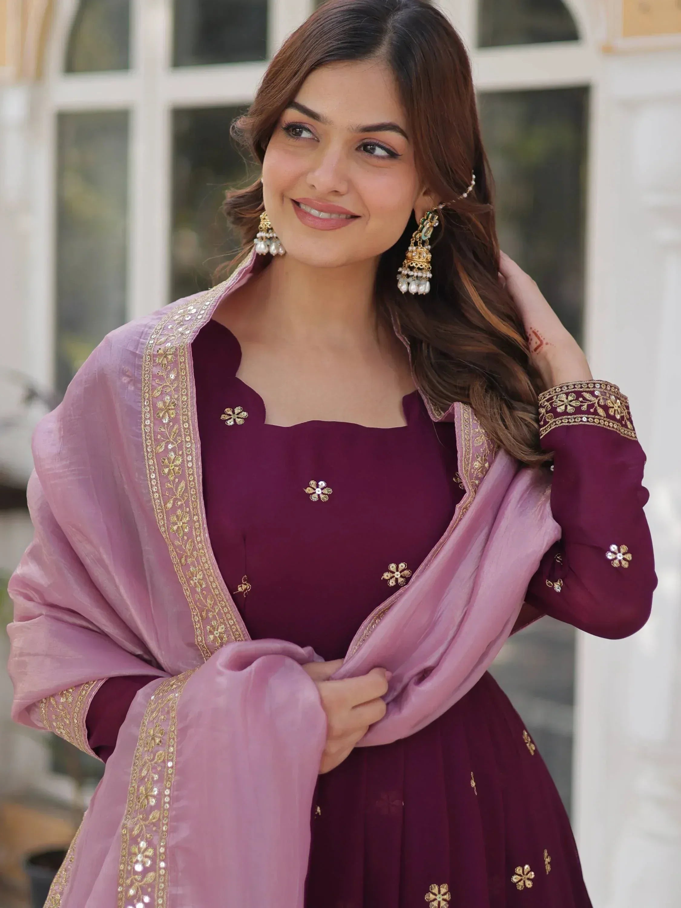 Elegant maroon ethnic gown with gold floral embroidery and pink dupatta, perfect for Indian celebrations.