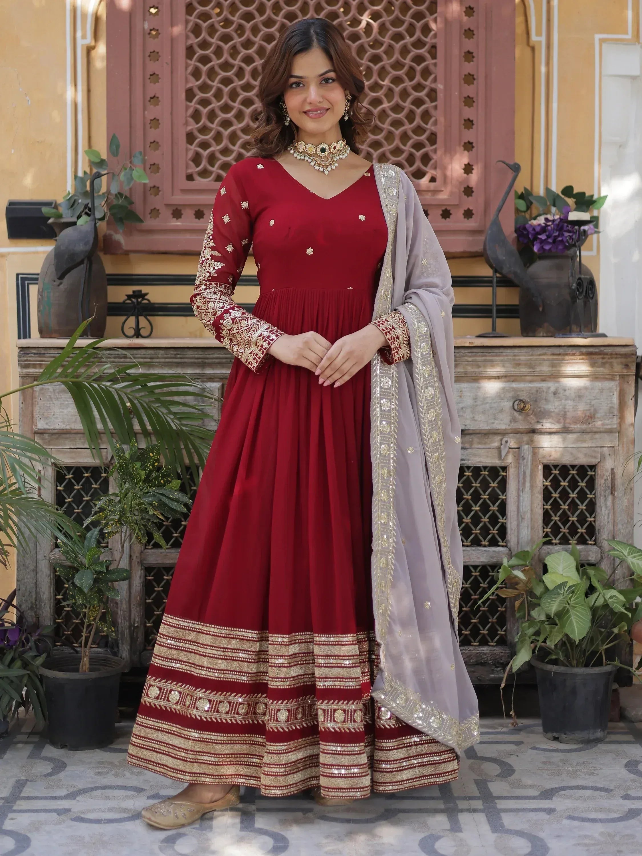 Woman in maroon embroidered Anarkali suit with gold details and dupatta, traditional Indian attire