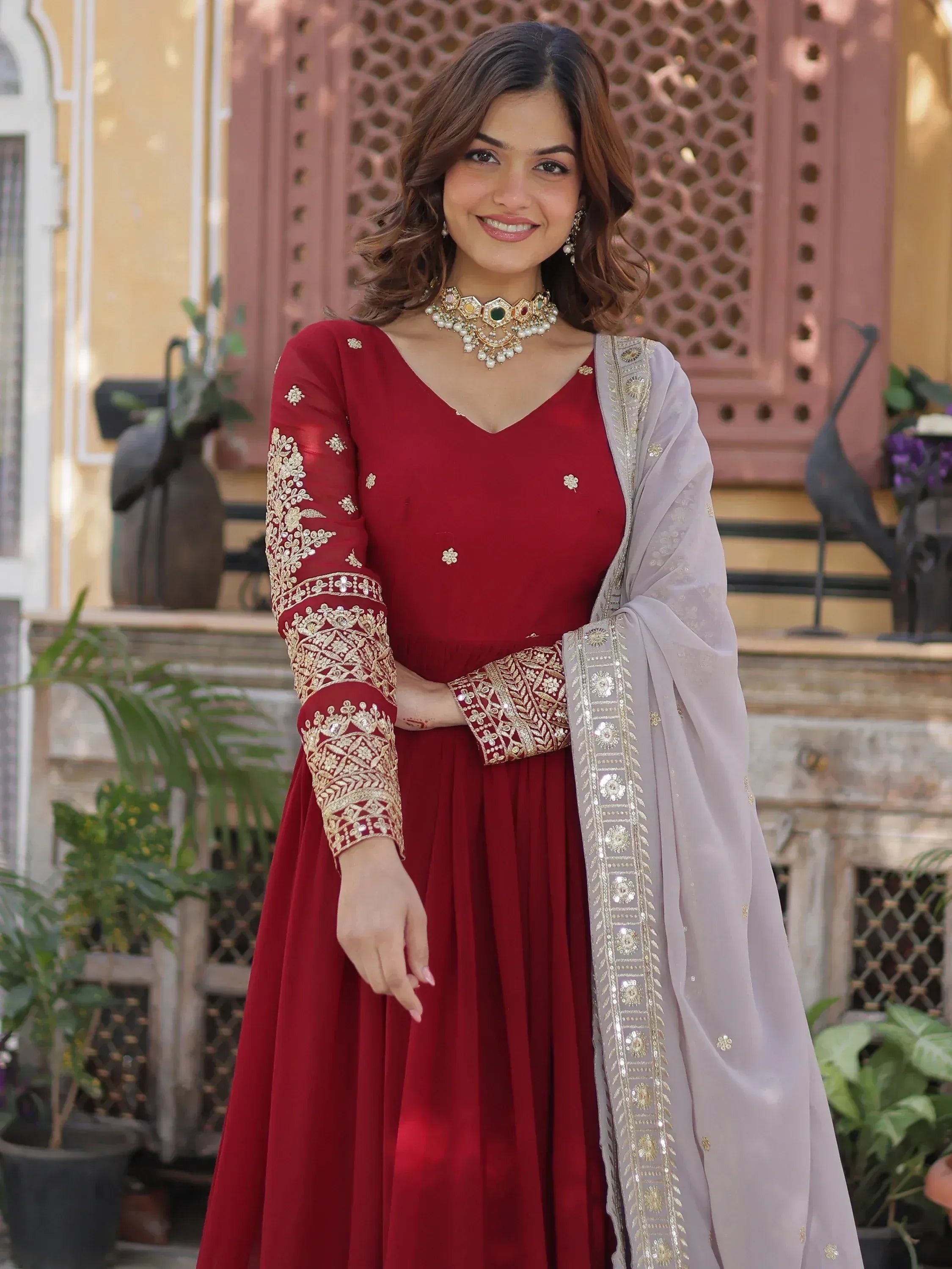 Woman in maroon embroidered Anarkali suit with beige dupatta, traditional Indian wear