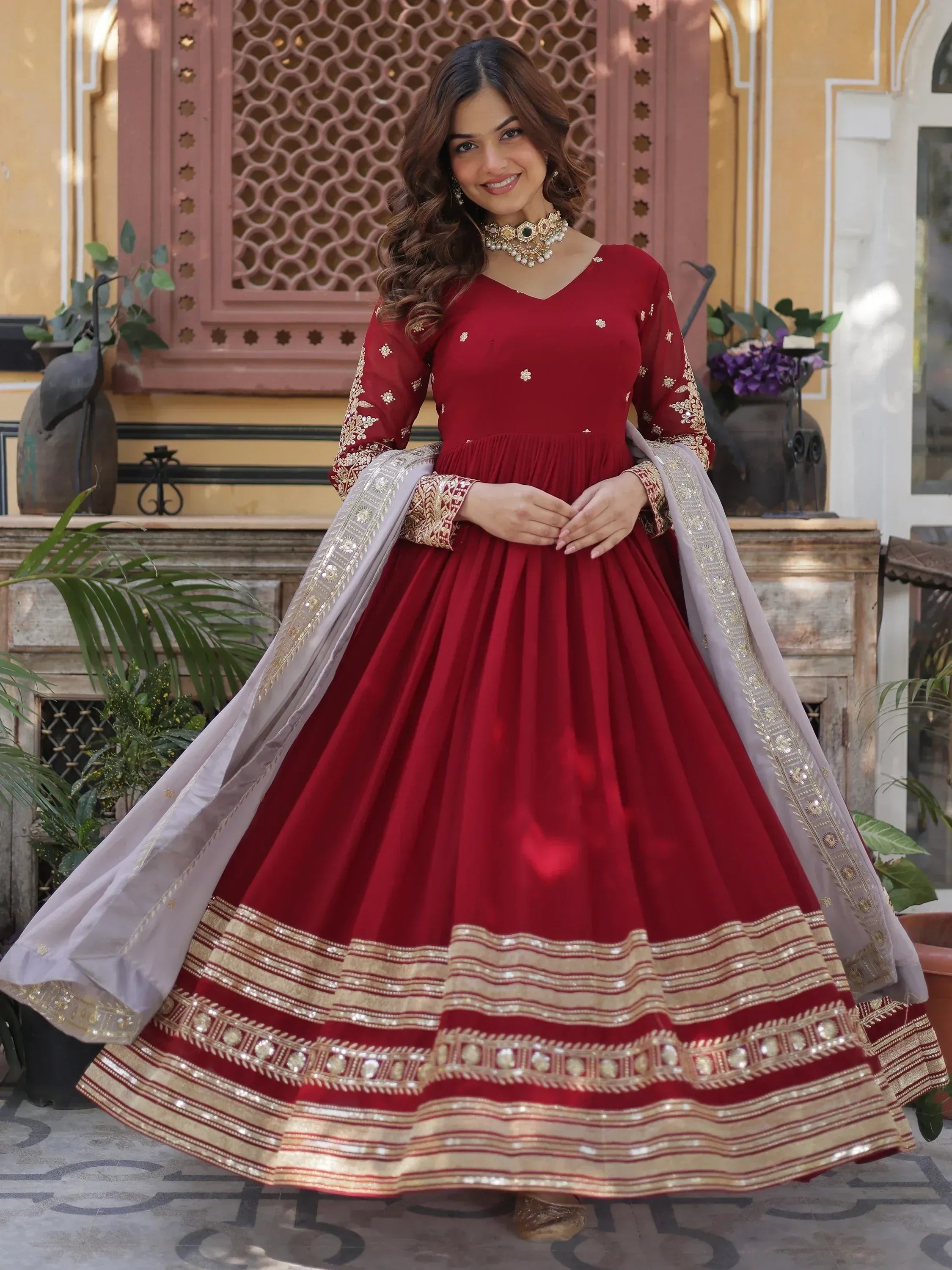 Woman in maroon embroidered Anarkali gown with gold border and dupatta, festive ethnic wear