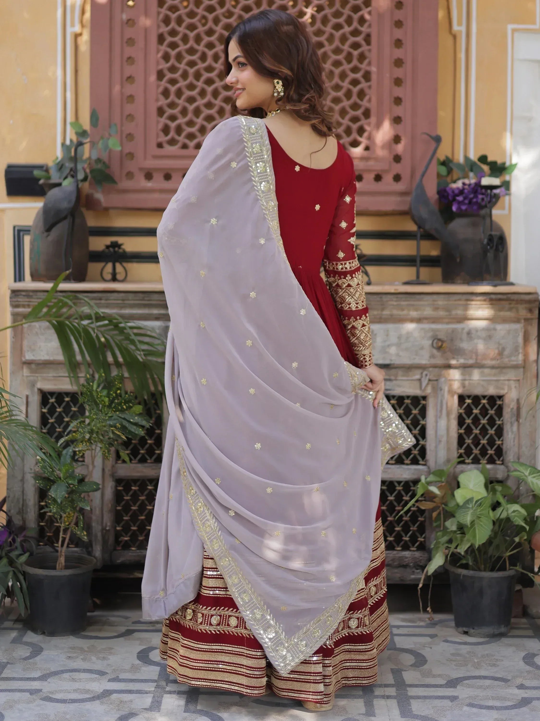 Woman in maroon embroidered lehenga choli with gold accents and net dupatta, traditional Indian attire