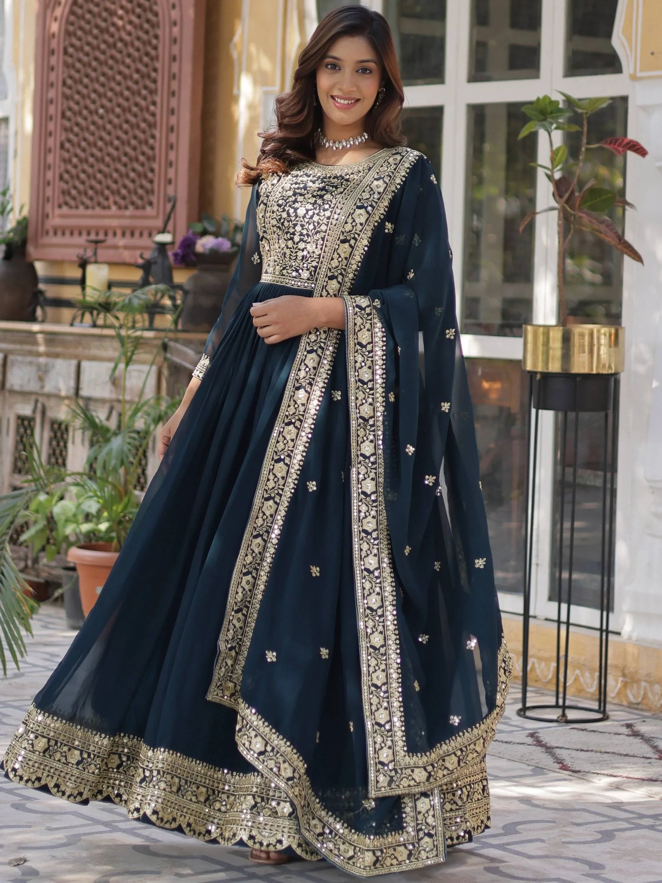 Woman in navy blue embroidered ethnic gown with gold detailing, traditional Indian attire