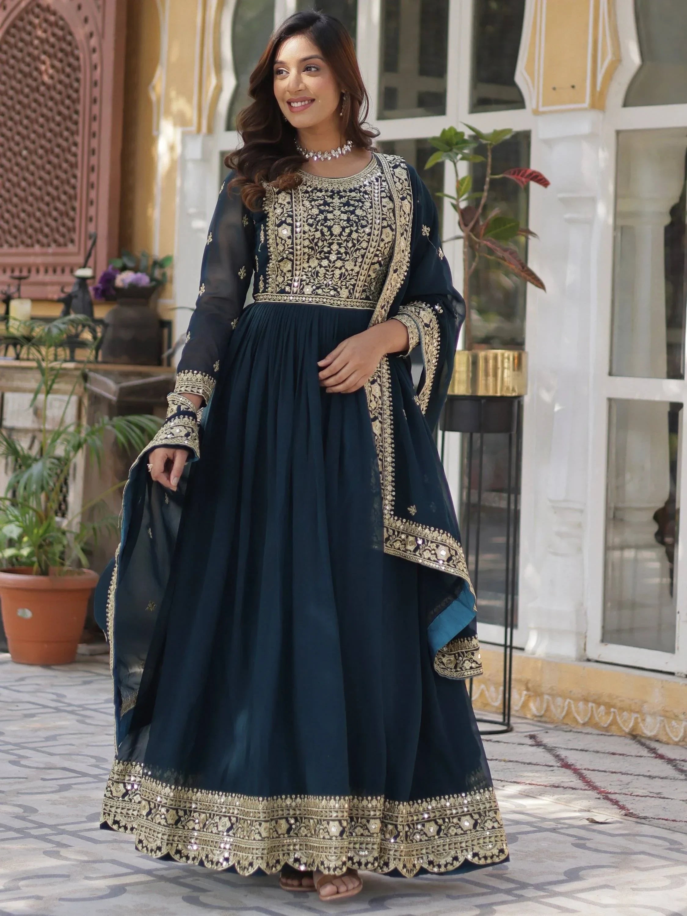 Woman in navy blue embroidered ethnic gown with gold detailing, outdoor setting