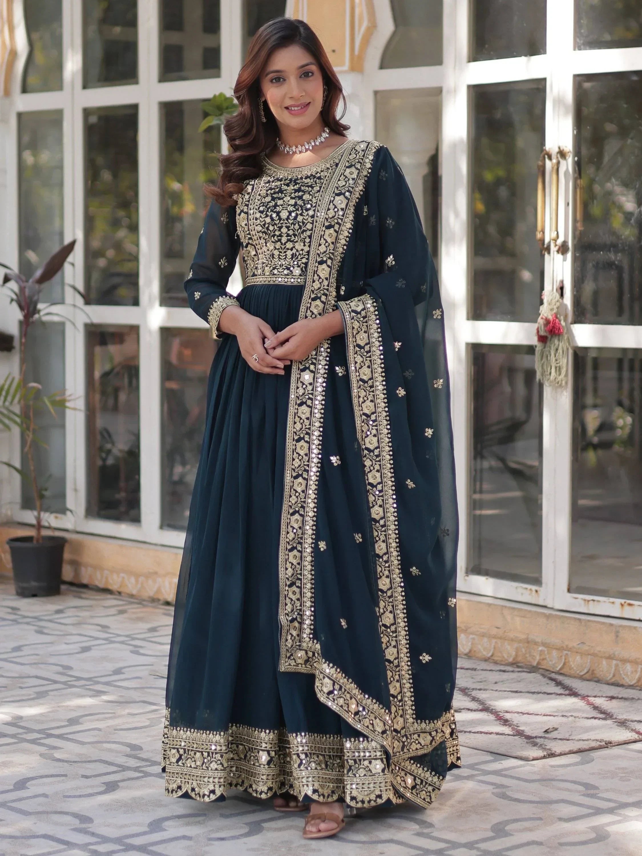 Woman wearing navy blue embroidered ethnic gown with gold detailing and dupatta