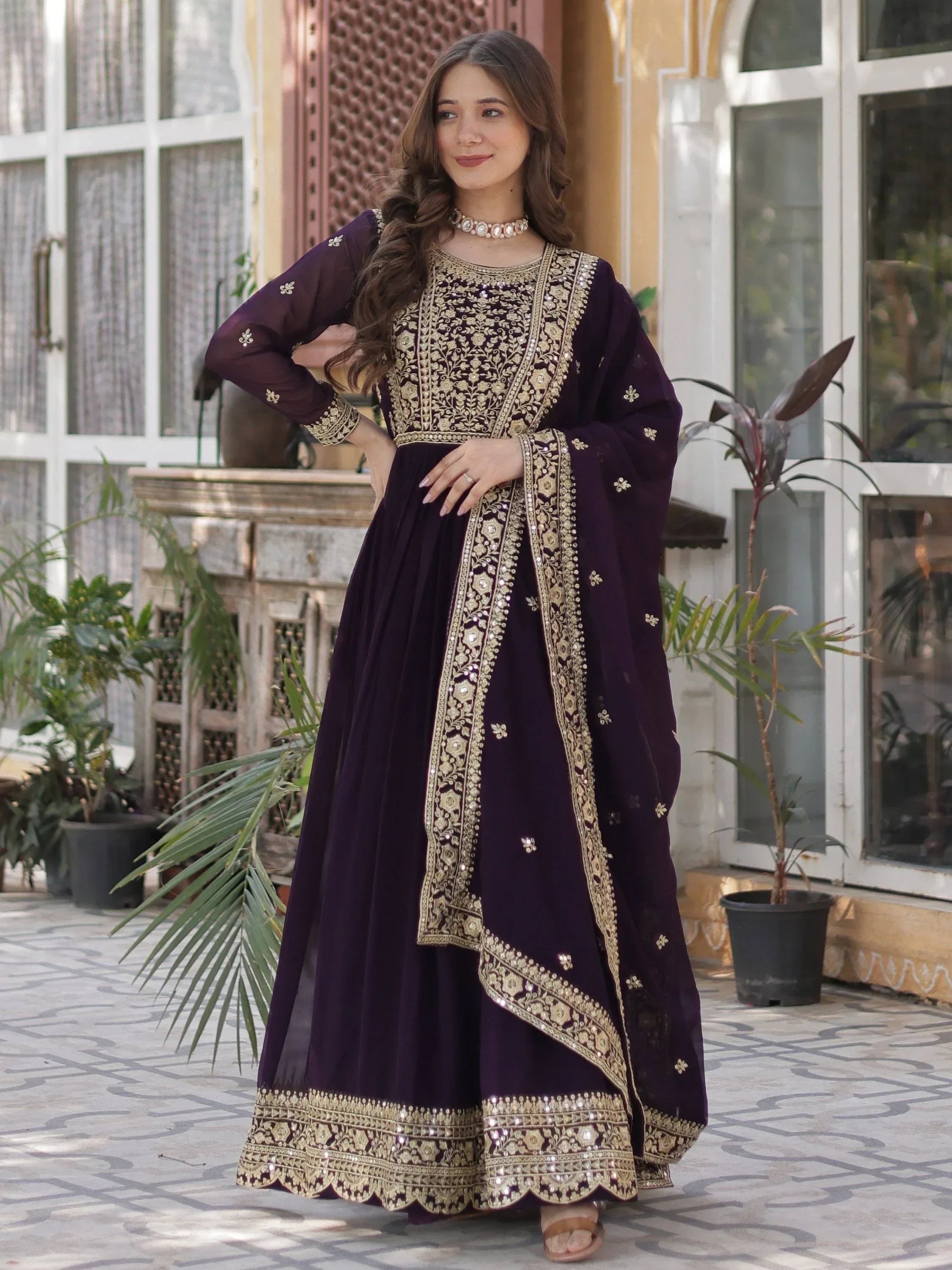Woman in wine-colored embroidered Anarkali gown with gold dupatta, Indian ethnic wear
