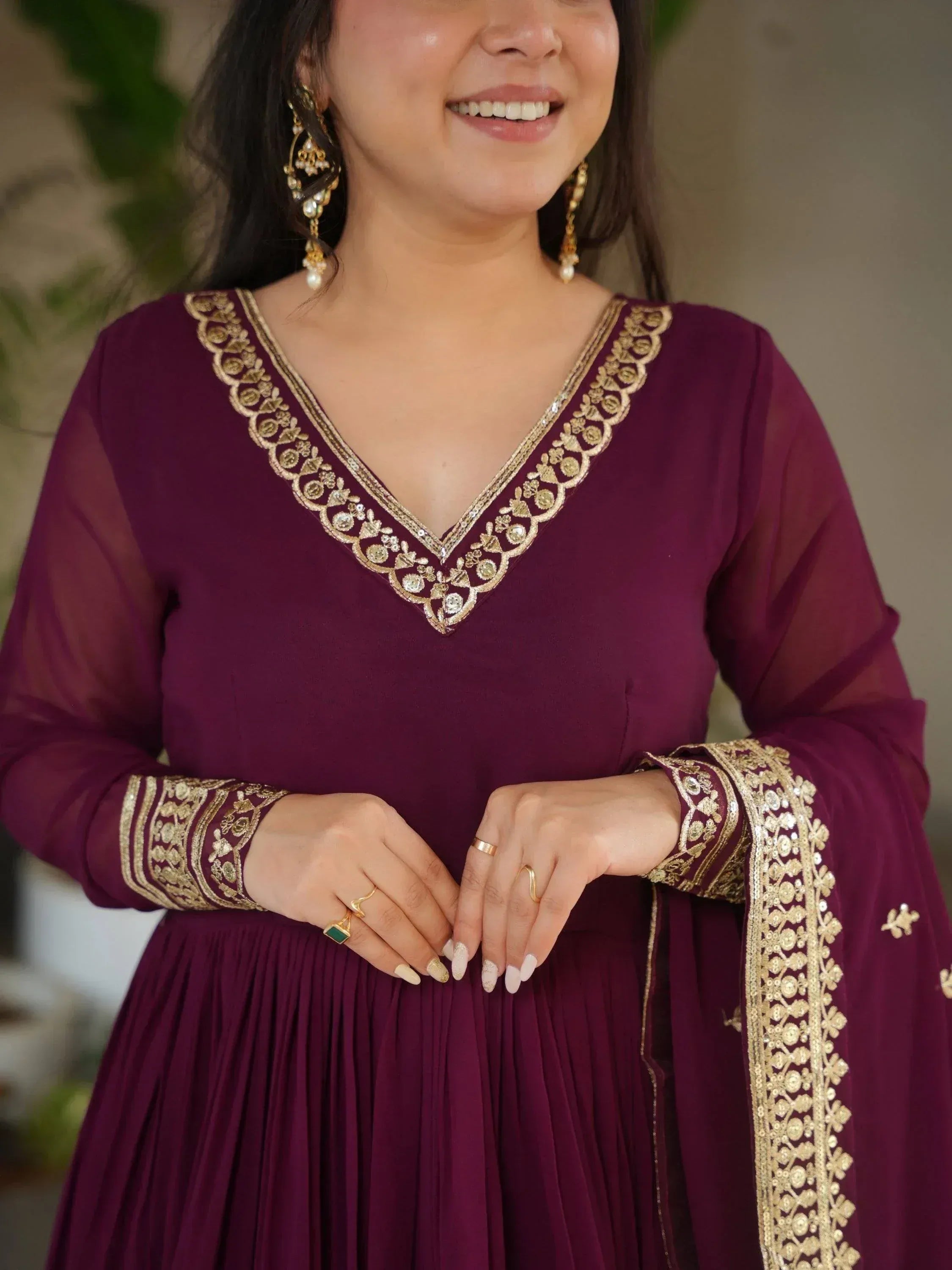 Woman in maroon ethnic gown with gold embroidery, perfect for Indian occasions and festive wear.