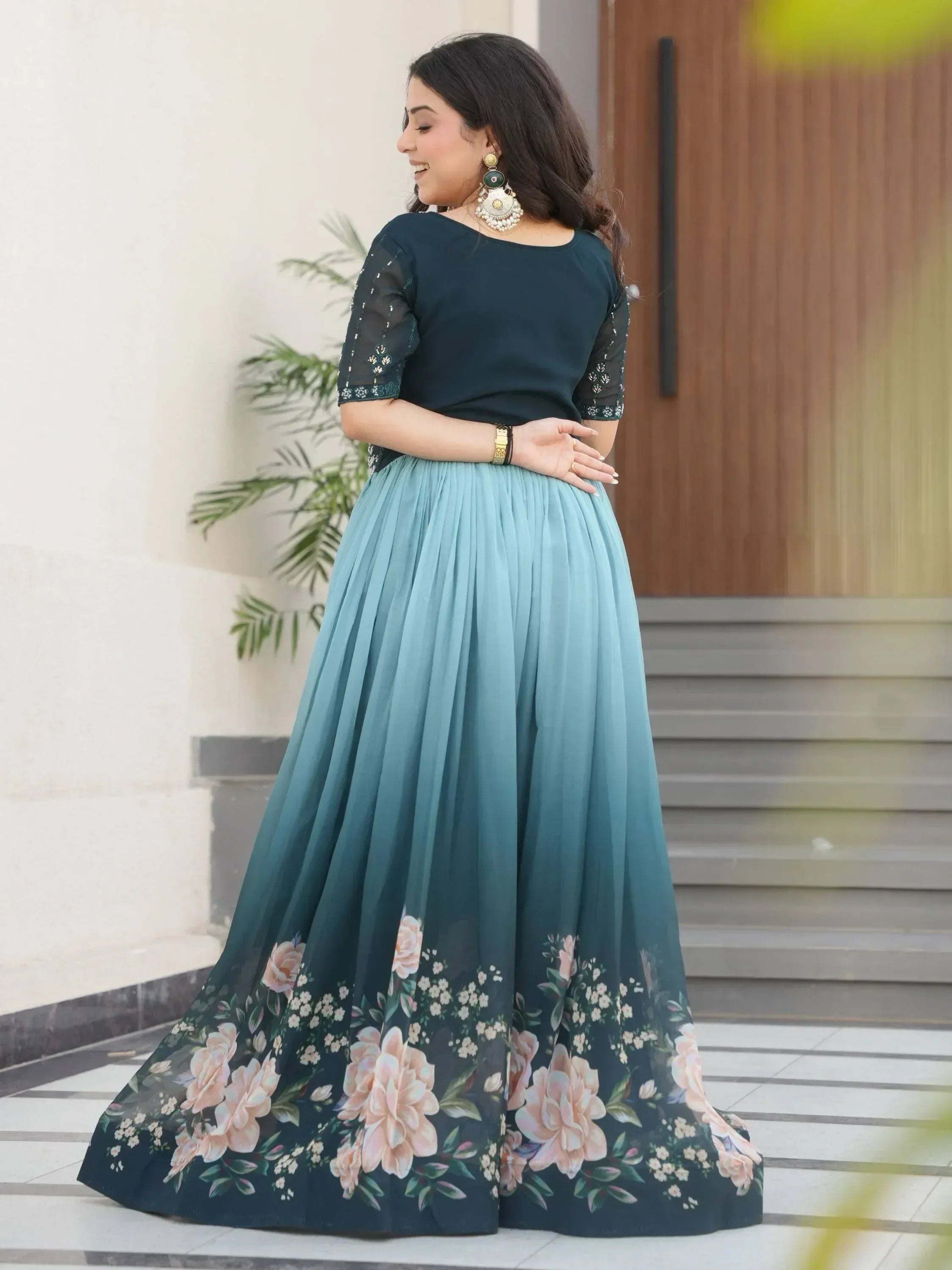 Woman in elegant teal floral ethnic gown with sheer sleeves, perfect for Indian occasions