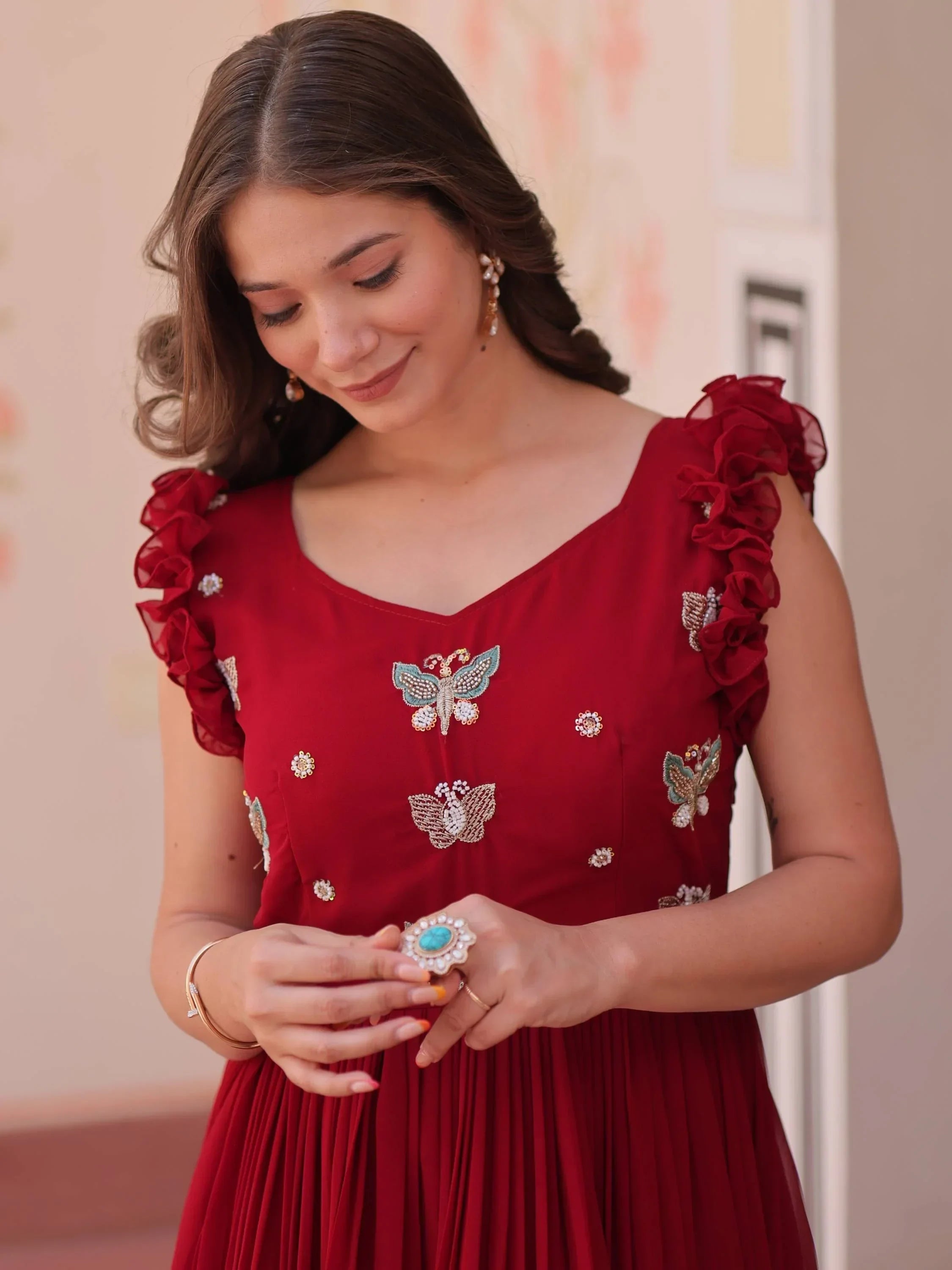 Woman in maroon ethnic gown with butterfly embroidery and ruffle sleeves