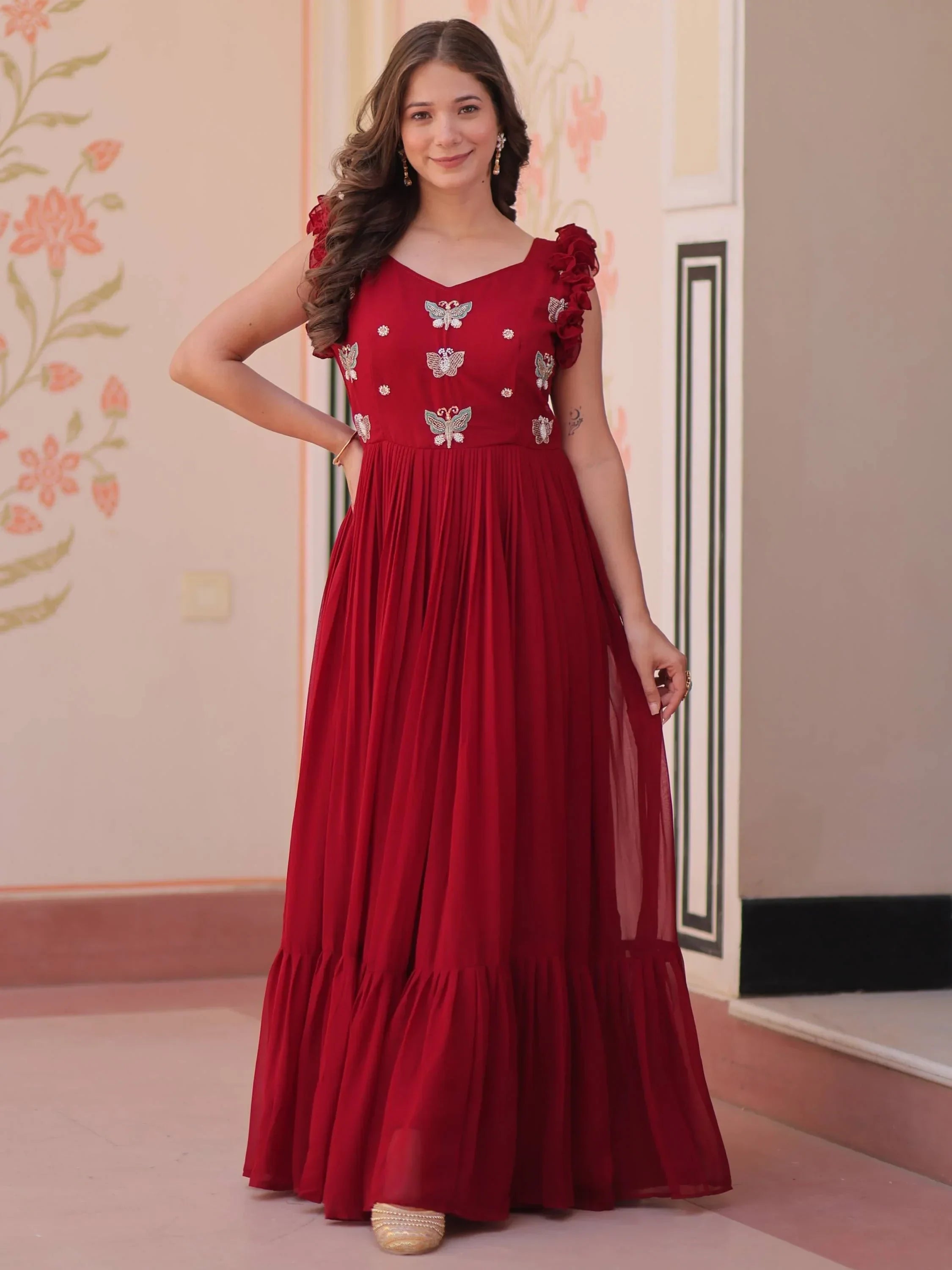 Woman wearing maroon ethnic gown with butterfly embroidery and ruffle sleeves indoors