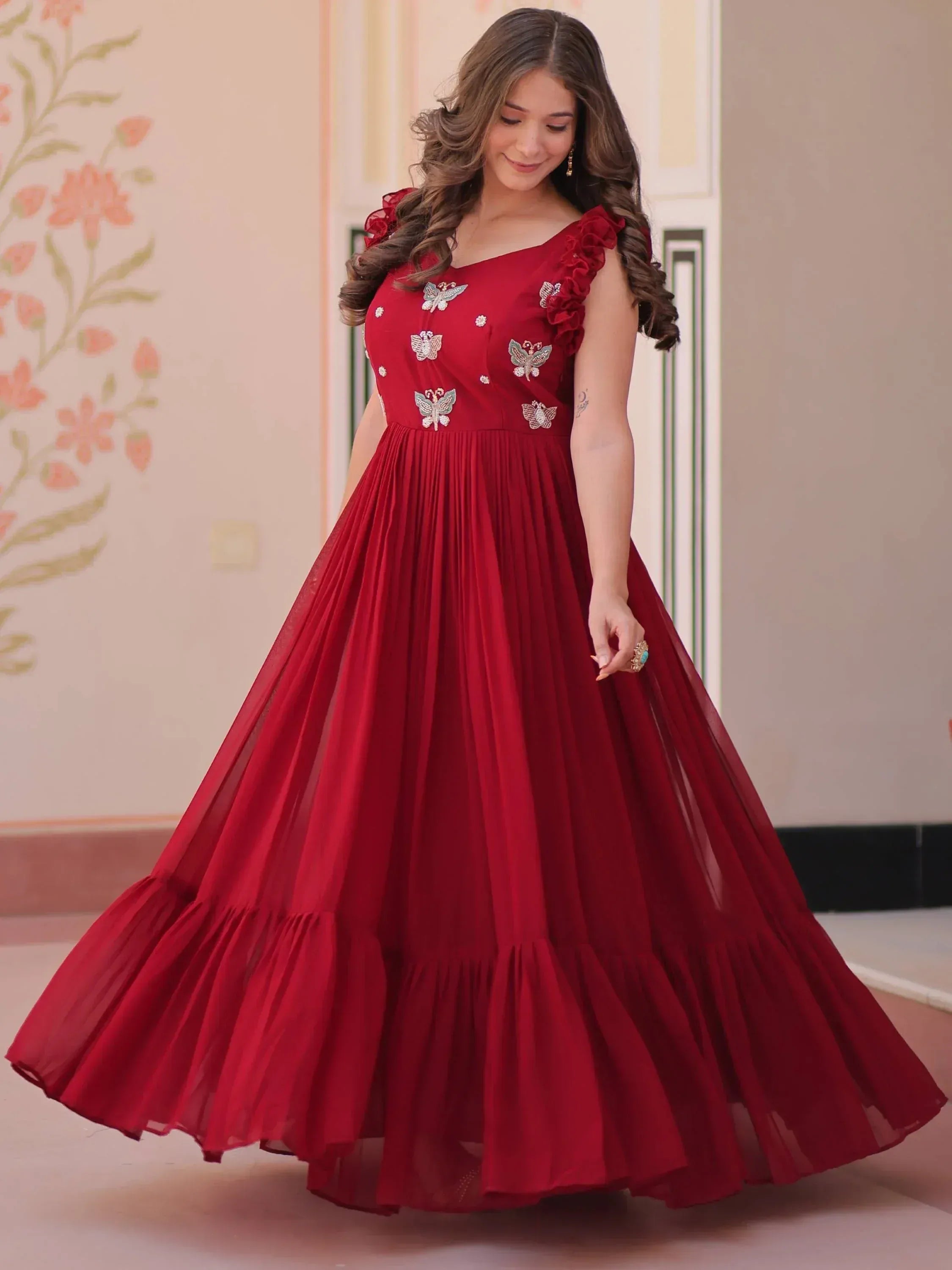 Red ethnic gown with butterfly embroidery and ruffled sleeves, perfect for Indian festive occasions.