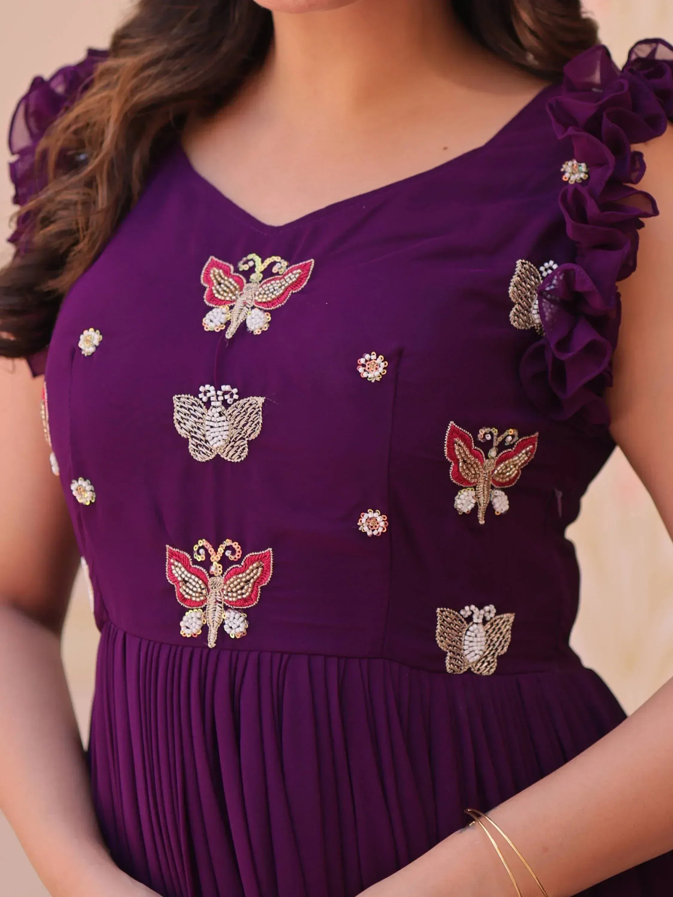 Purple ethnic gown with butterfly embroidery, ruffled sleeves, and floral embellishments for festive occasions.