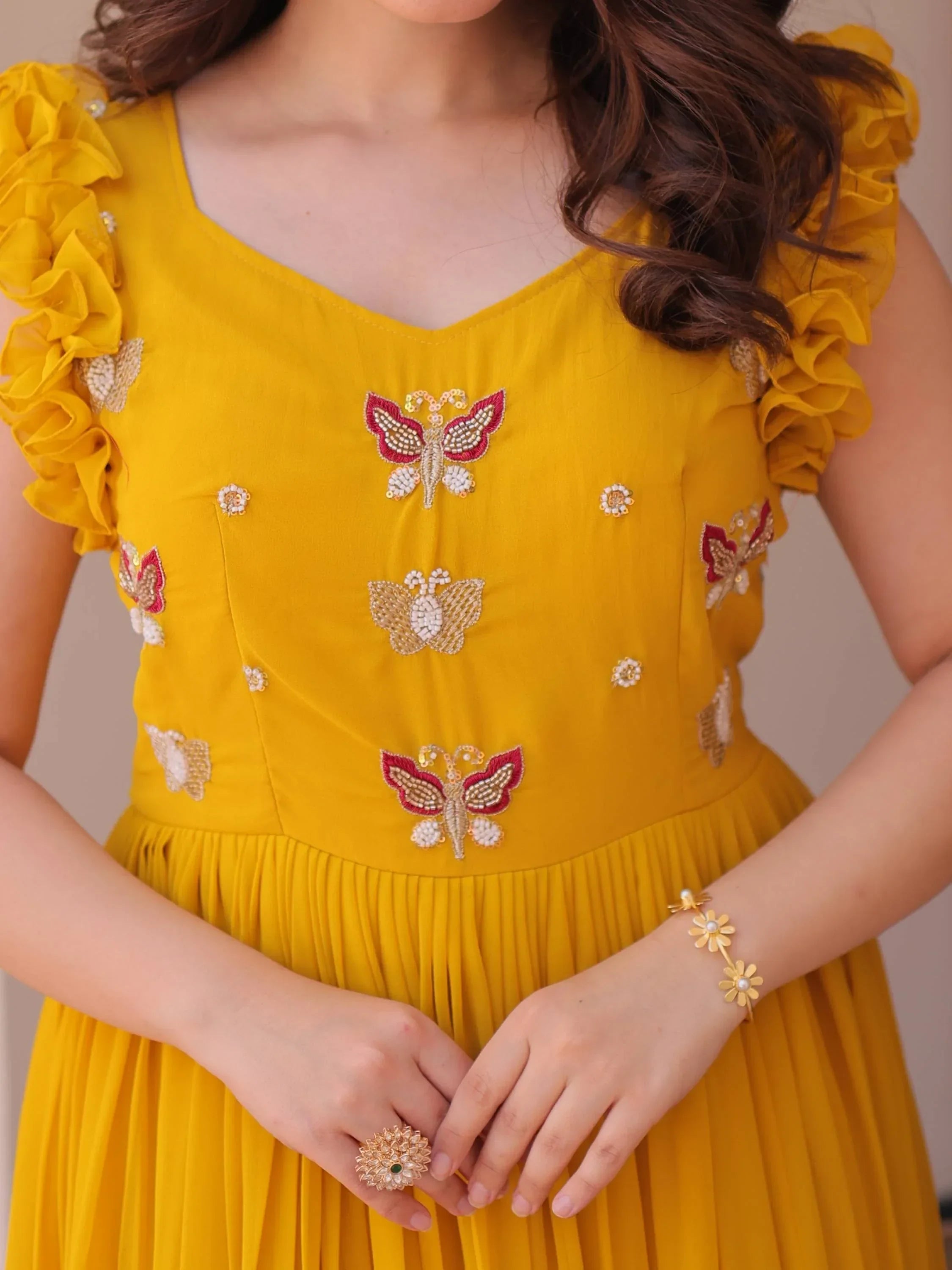Yellow ethnic gown with butterfly embroidery and ruffled sleeves, floral jewelry accents