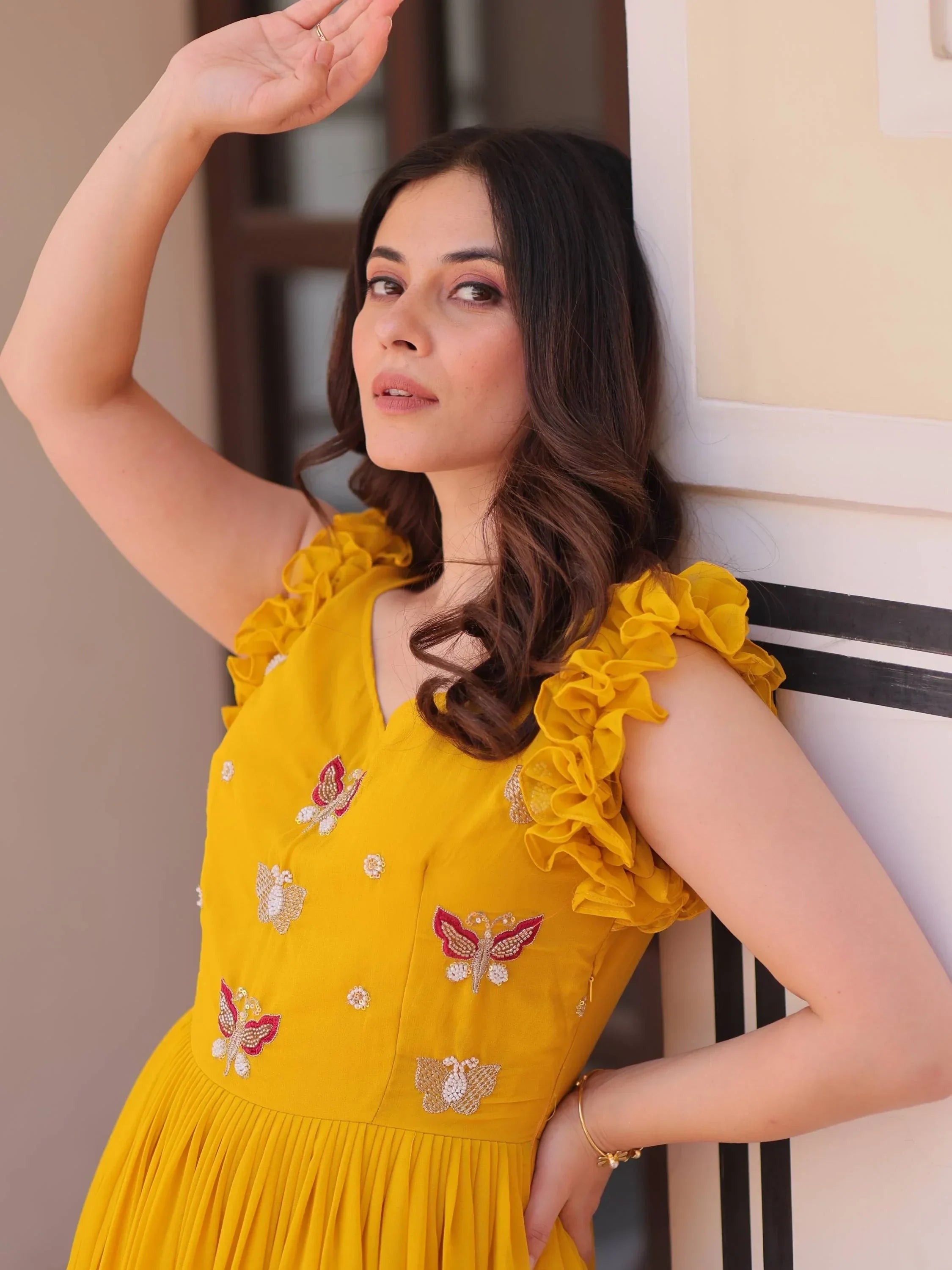 Woman in a yellow ethnic dress with butterfly embroidery and ruffled sleeves