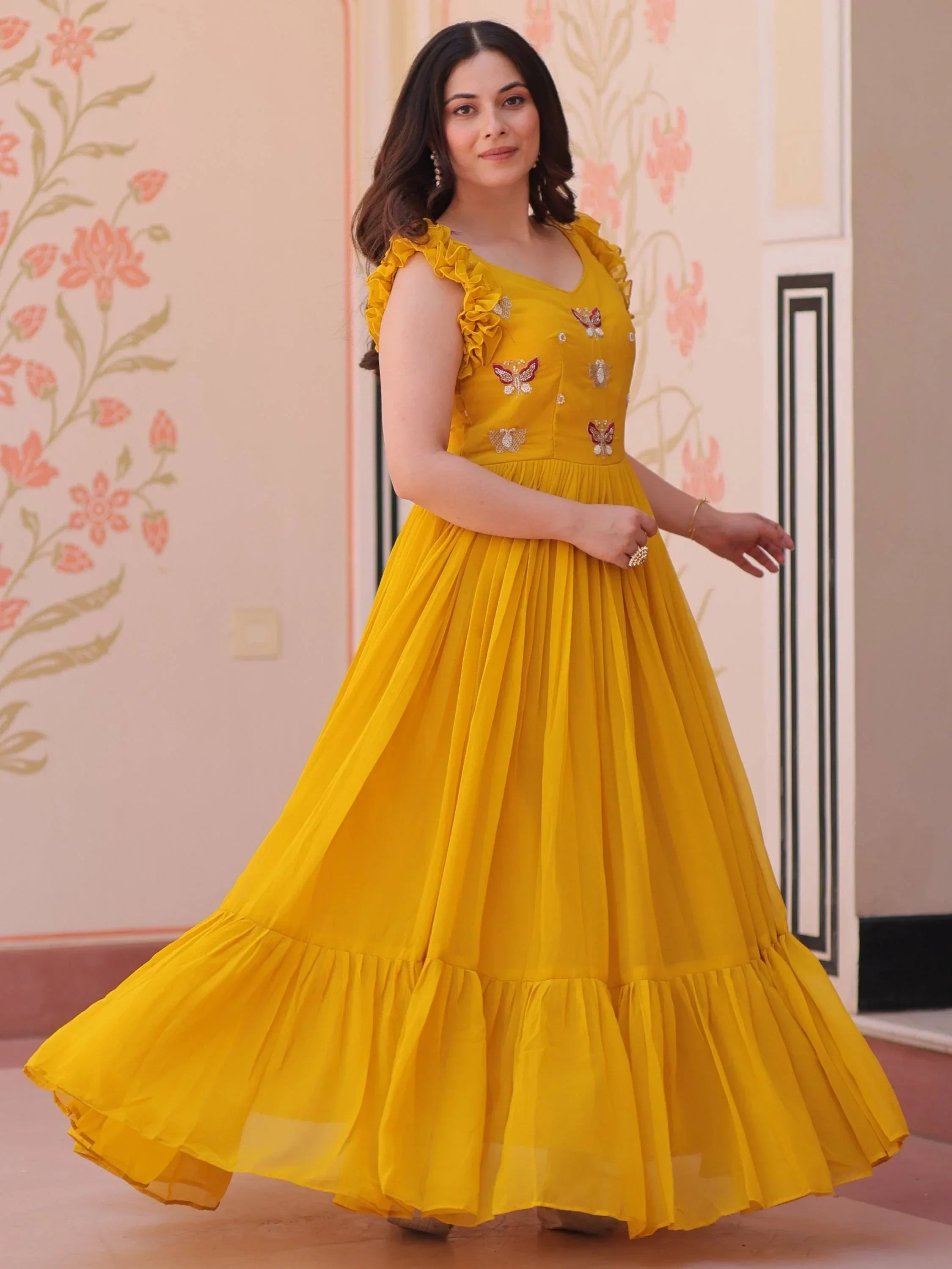 Woman in yellow embroidered ethnic gown with ruffled sleeves and flared skirt