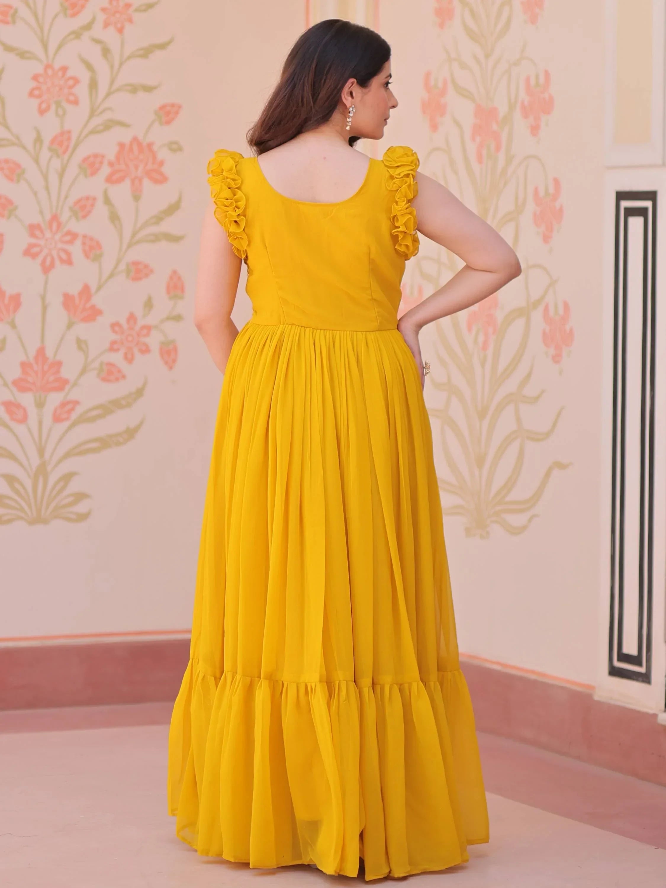 Woman wearing a yellow ethnic gown with ruffle sleeves, standing indoors