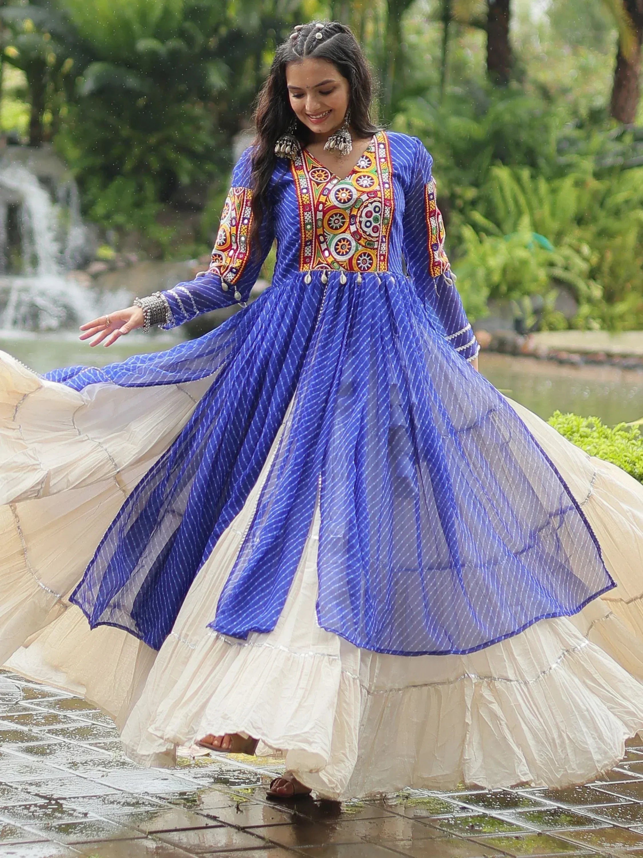 Woman twirling in blue embroidered ethnic gown with layered skirt, perfect for festive occasions