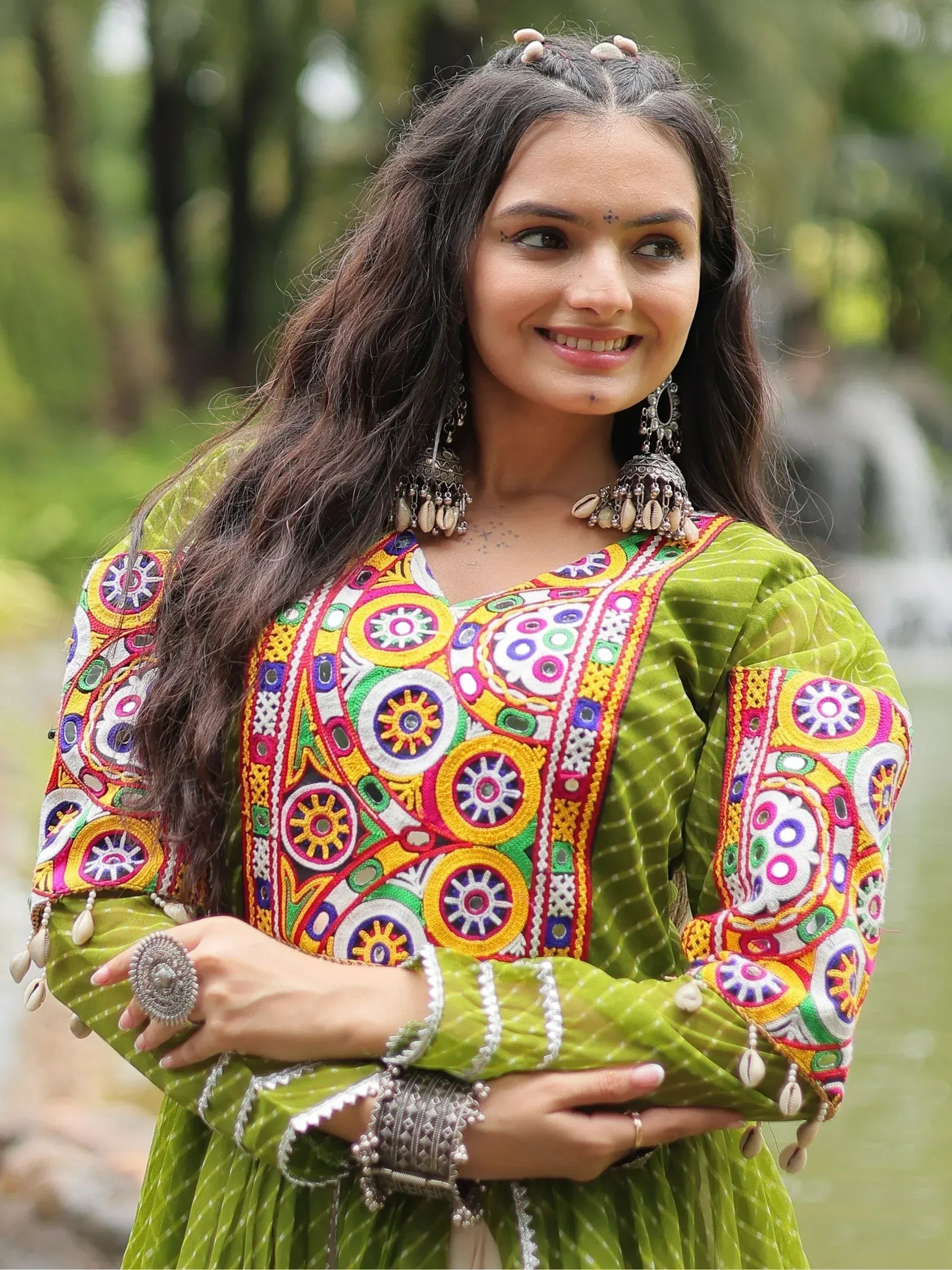 Woman in vibrant green embroidered ethnic kurta with mirror work, shell jewelry, and traditional Indian attire