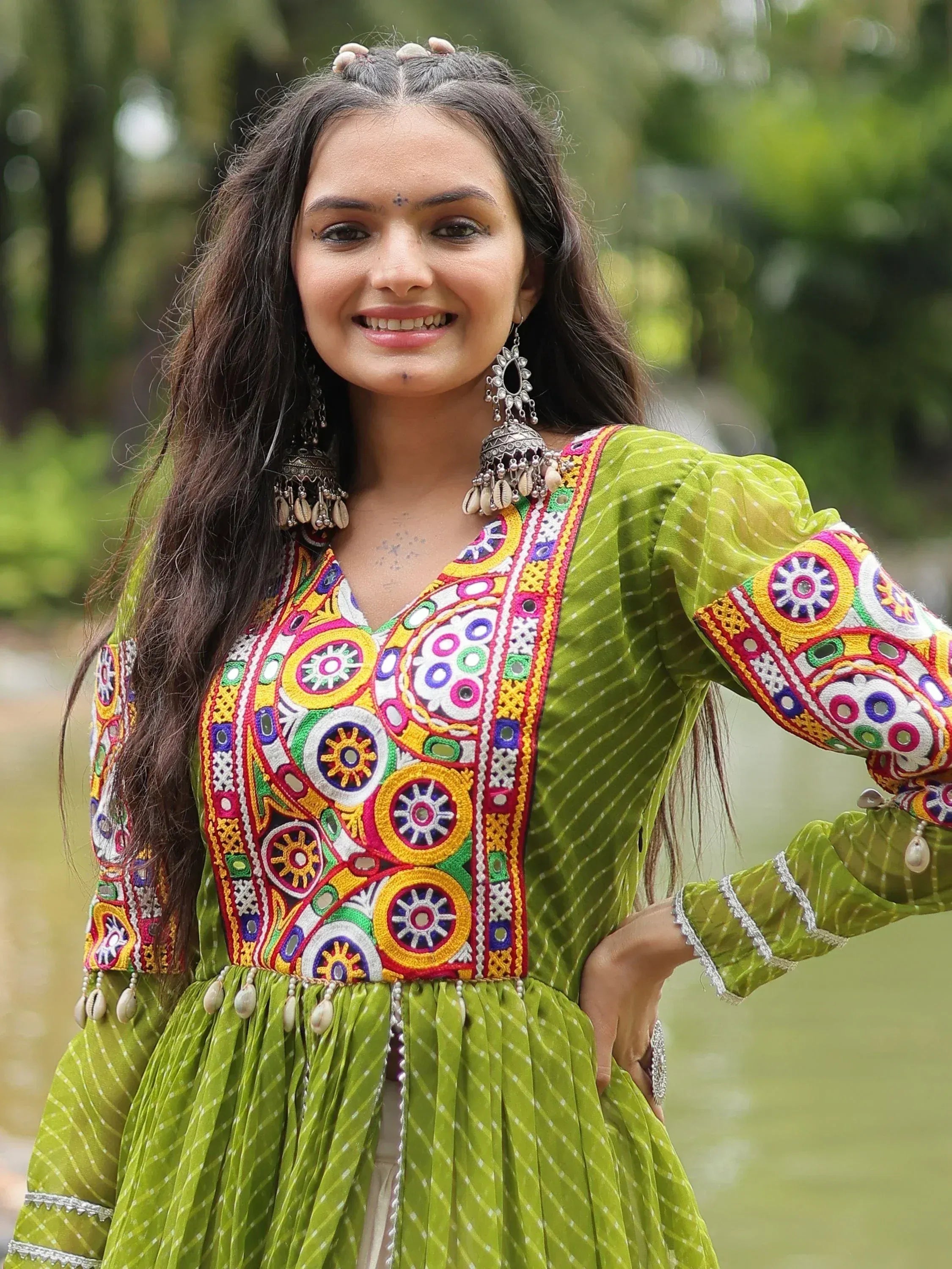 Woman in vibrant green embroidered ethnic gown with mirror work, perfect for Indian festive occasions.