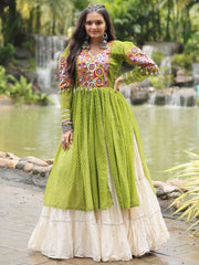 Woman wearing green and cream traditional Indian gown with embroidery, outdoor waterfall backdrop