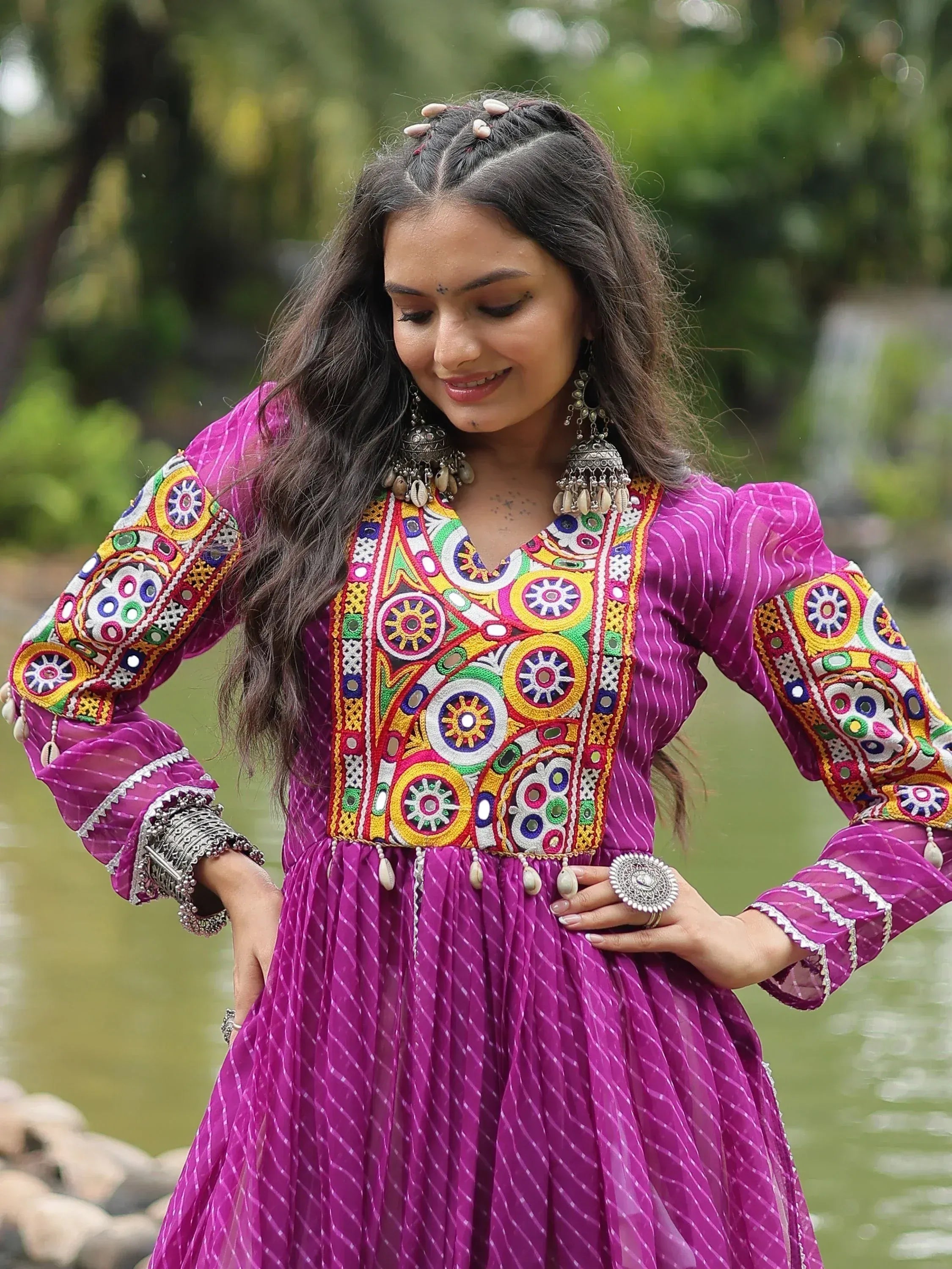 Woman in vibrant purple ethnic gown with colorful mirror embroidery, outdoors