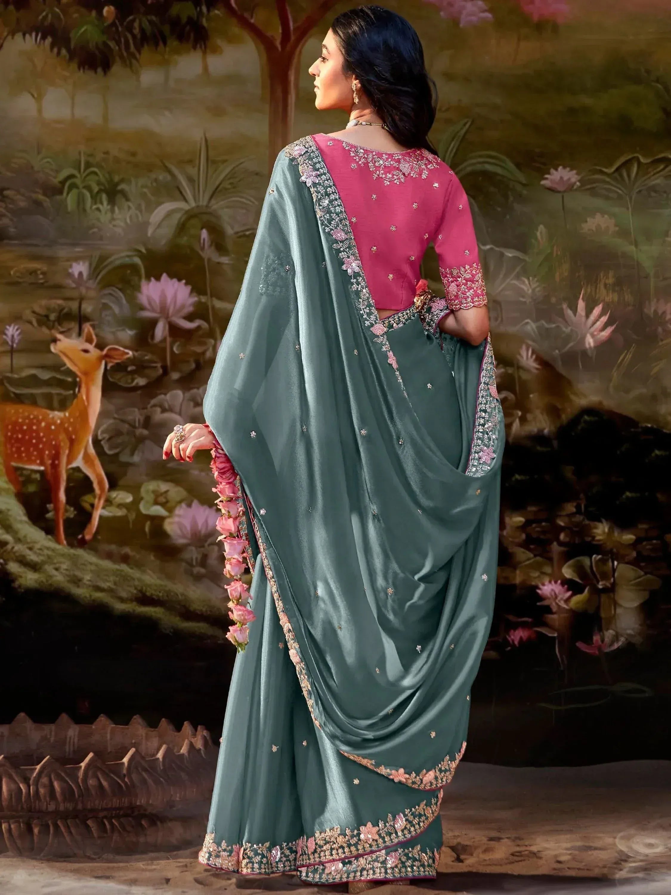 Woman in teal saree with pink floral embroidery, paired with matching blouse, ideal for Indian ethnic occasions