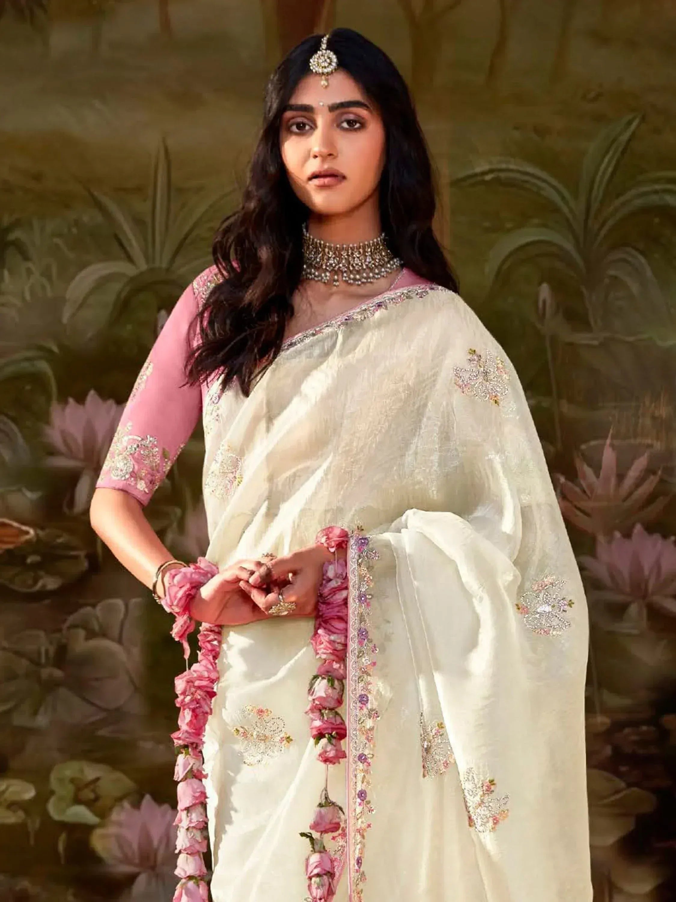 Elegant ivory saree with pink floral embroidery, paired with a pink blouse and traditional jewelry for Indian ethnic wear.
