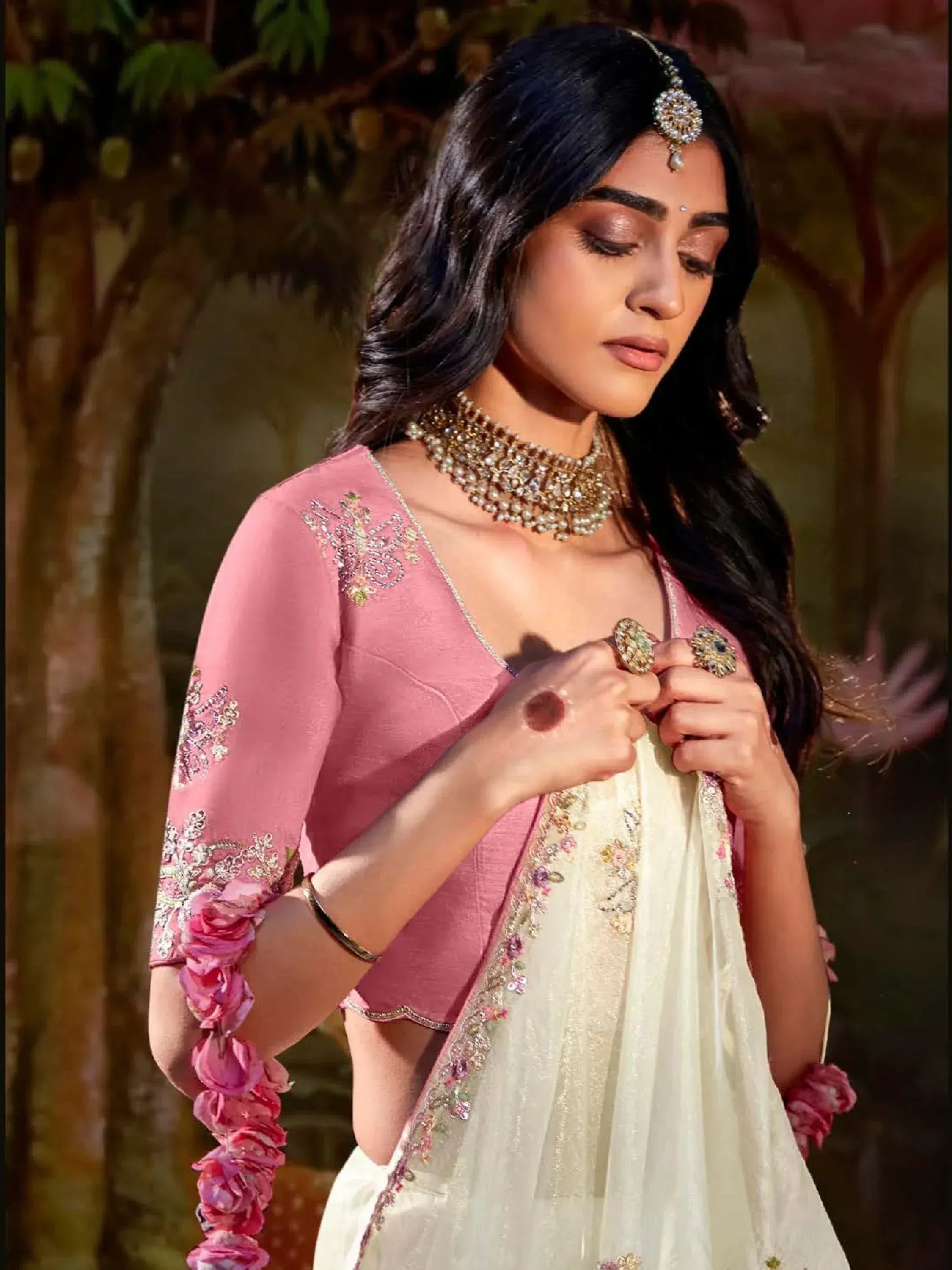 Woman in pink embroidered blouse and white lehenga with floral details, traditional Indian ethnic wear