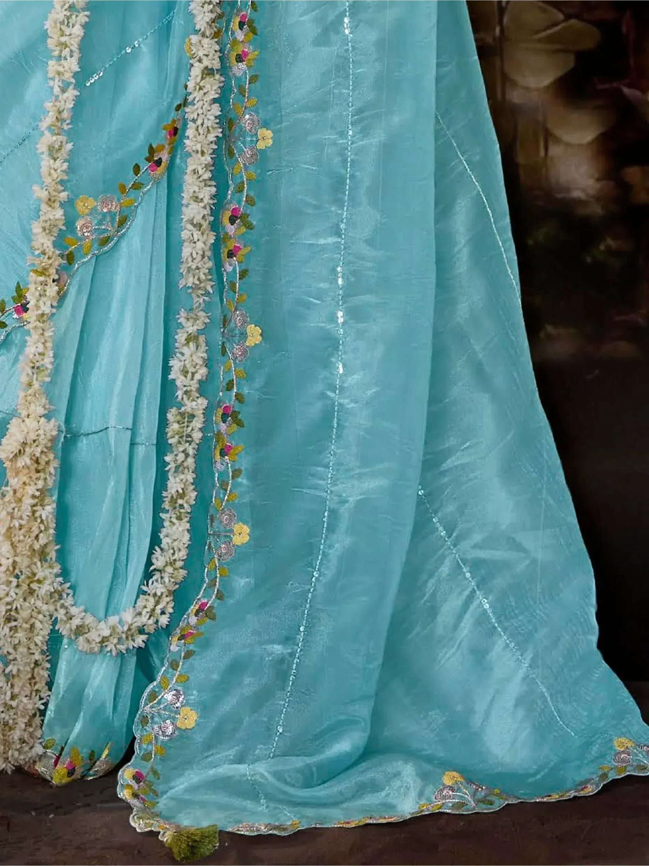 Turquoise ethnic gown with floral embroidery and white flower garland, perfect for Indian occasions