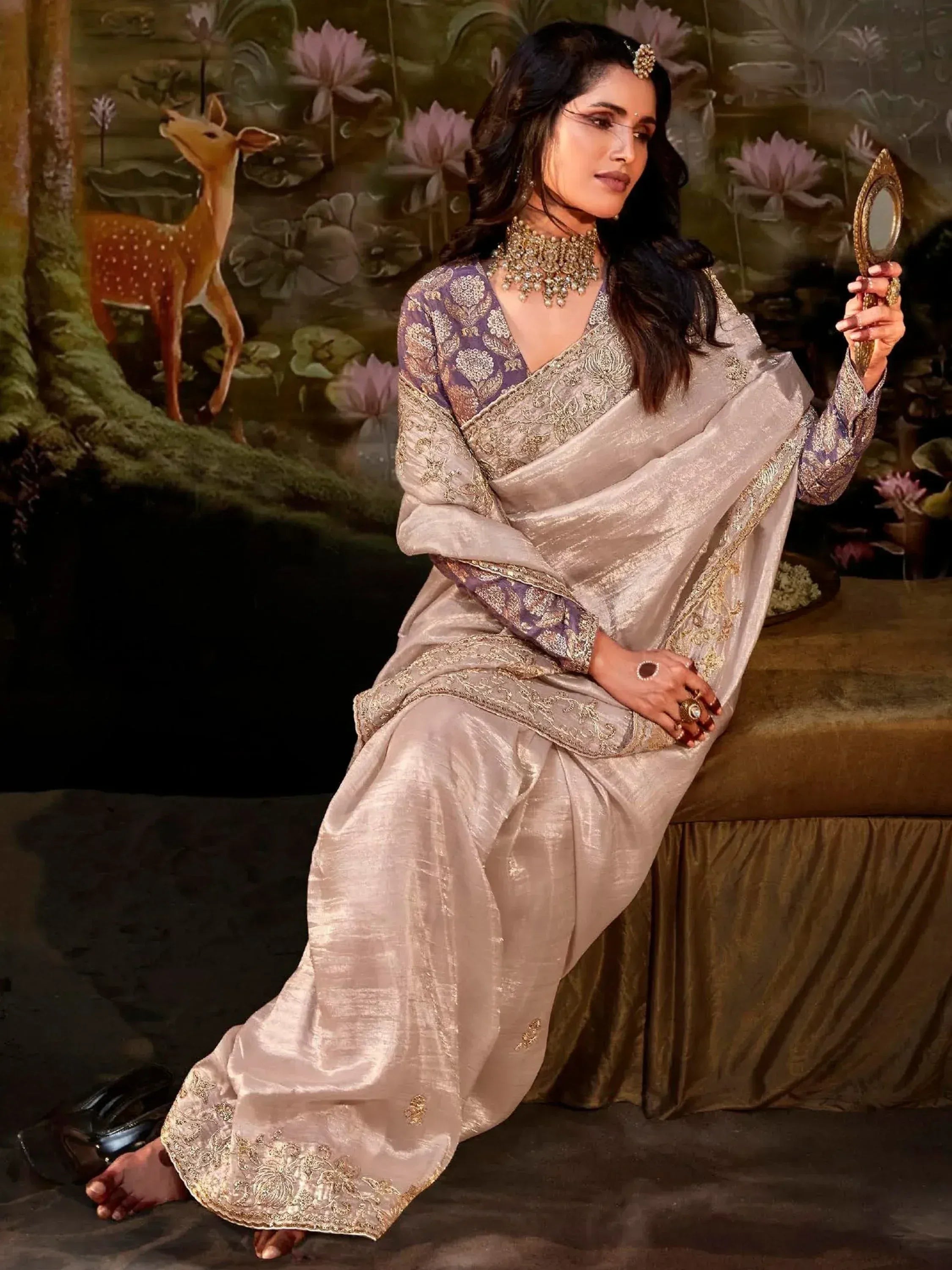 Elegant woman in designer Indian saree with gold embroidery, holding mirror, traditional ethnic wear