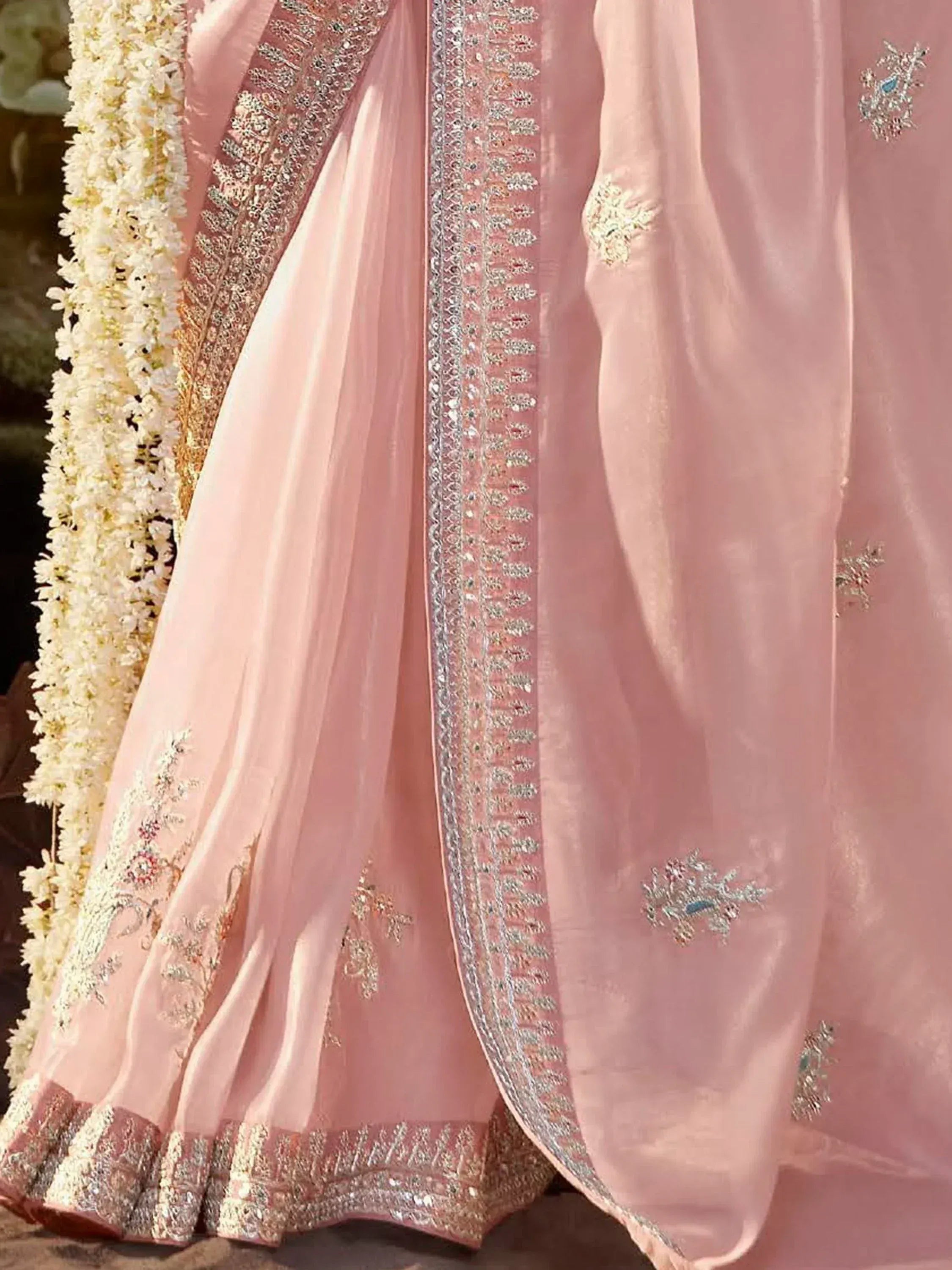 Pink designer lehenga choli with heavy embroidery and floral garland backdrop