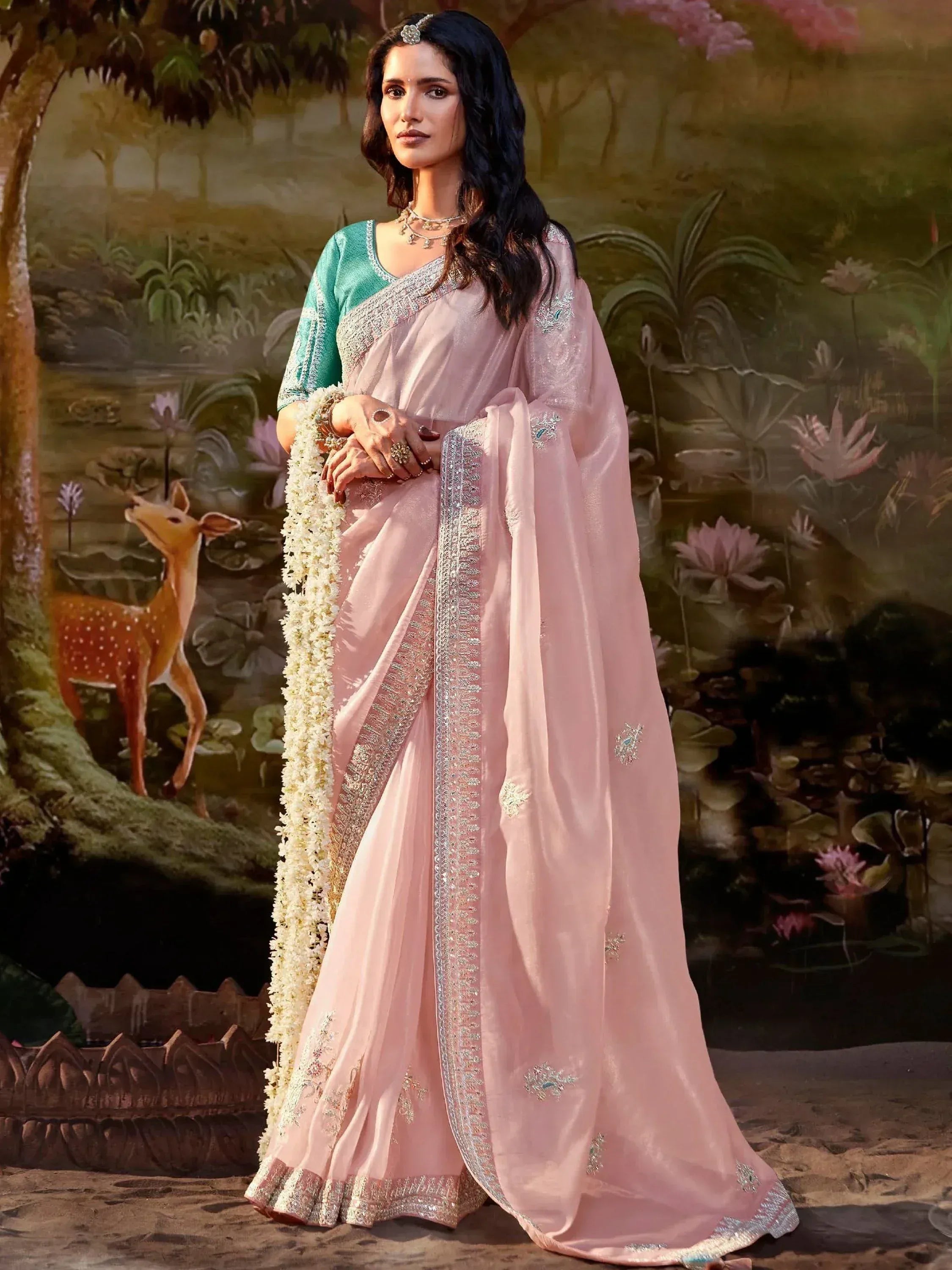 Pink embroidered saree with green blouse, floral garland, and traditional jewelry for Indian ethnic wear