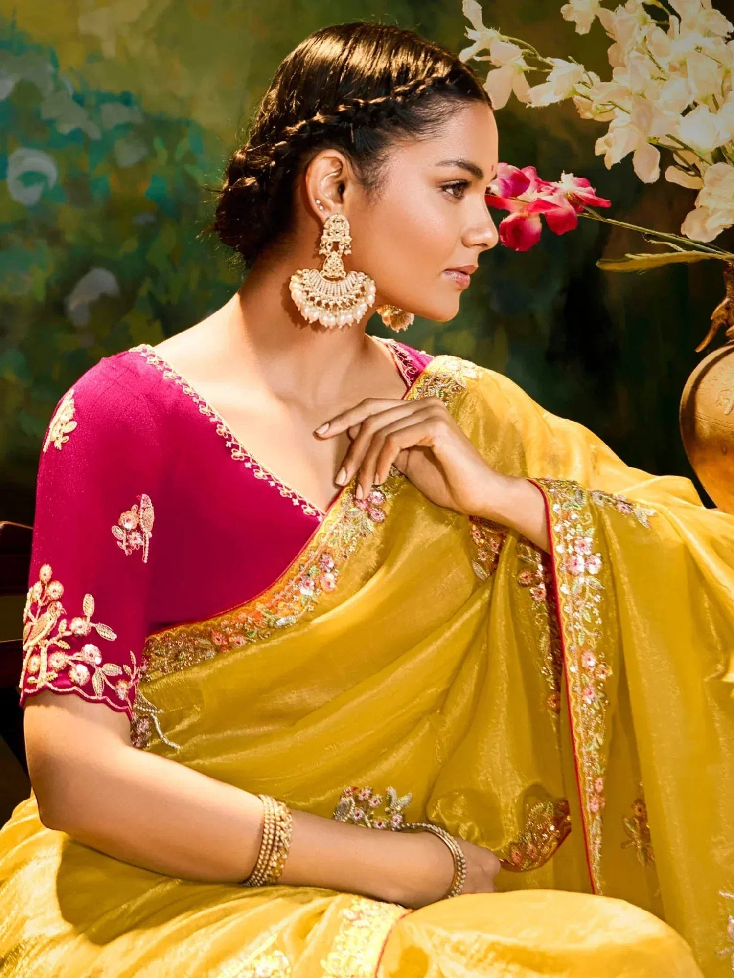 Elegant woman in yellow saree with pink blouse, floral embroidery, and traditional jewelry