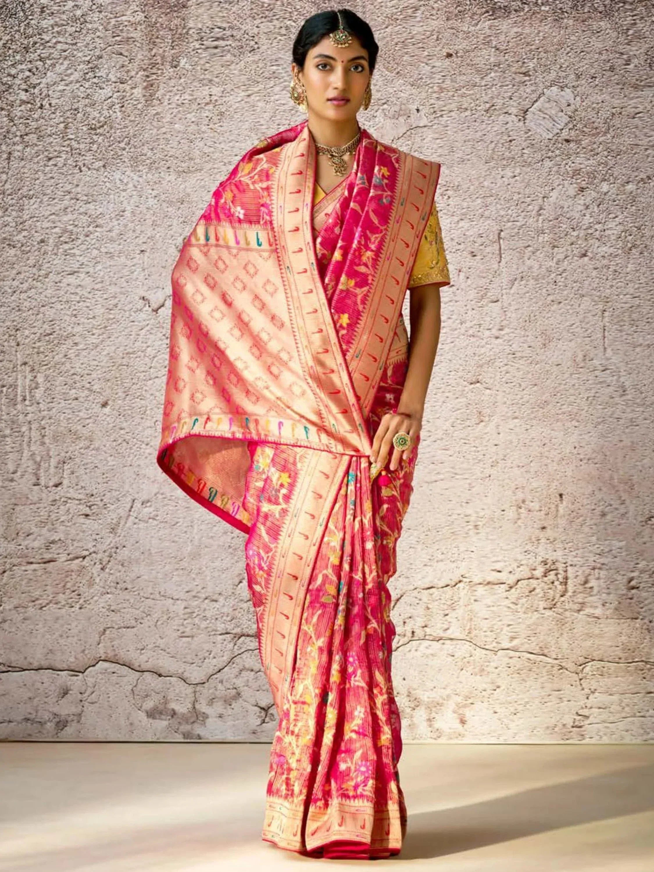 Pink and gold floral saree with intricate border, styled with traditional jewelry for ethnic wear