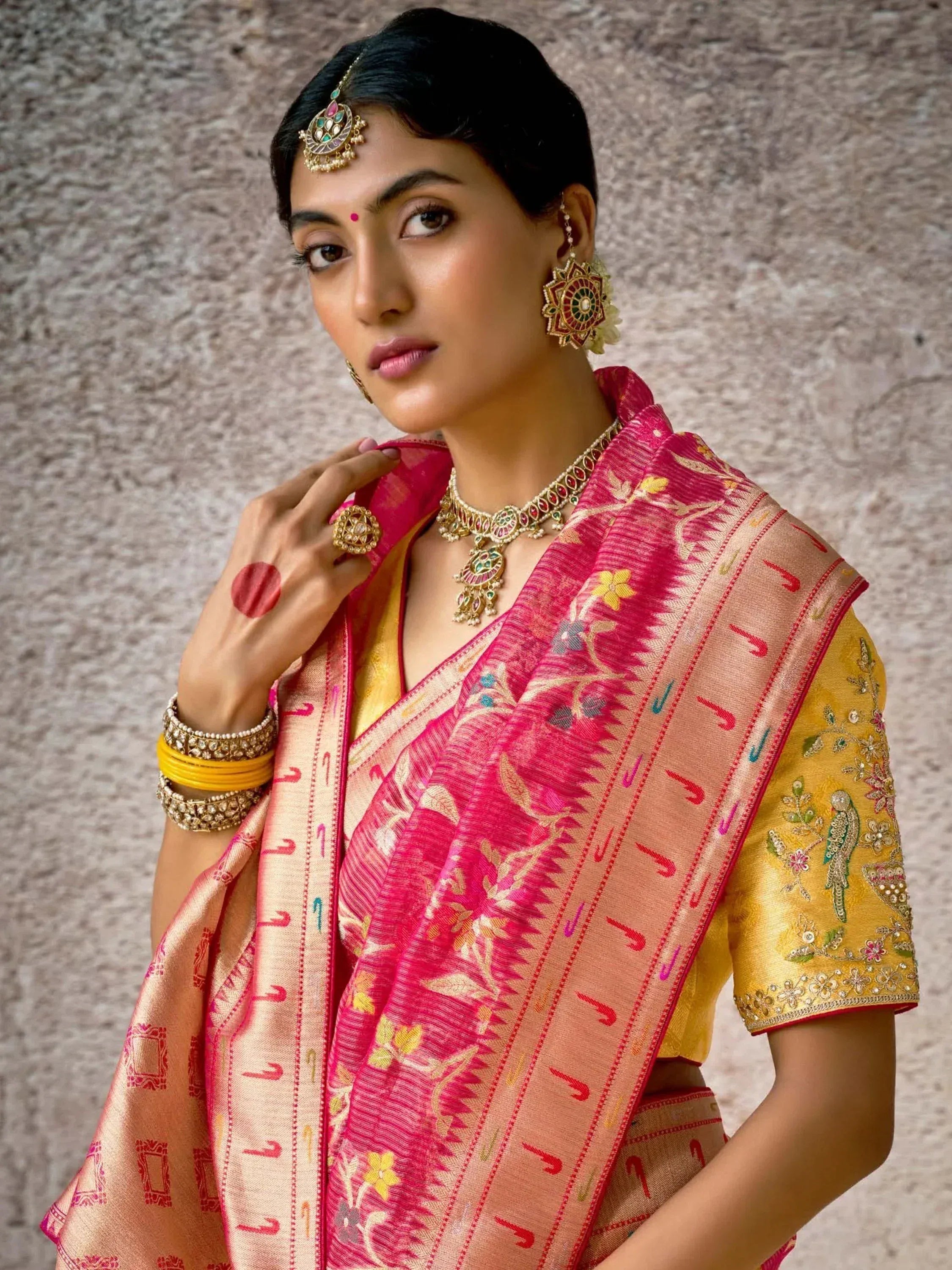 Woman in vibrant pink and gold embroidered saree with traditional Indian jewelry, perfect for ethnic occasions.