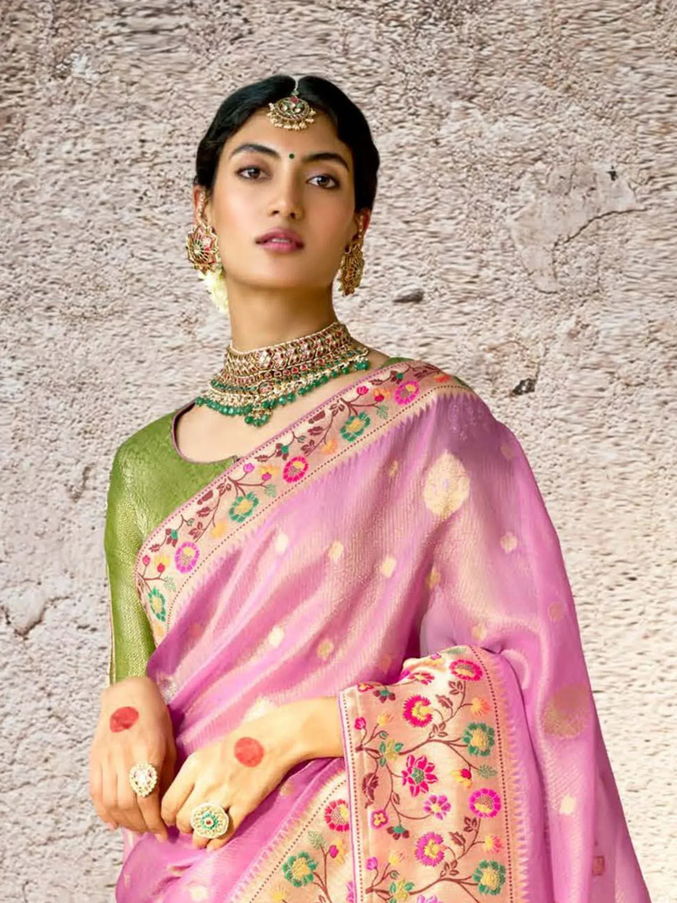 Woman in pink floral saree with green blouse, traditional Indian jewelry, and bindi, styled for ethnic occasions.