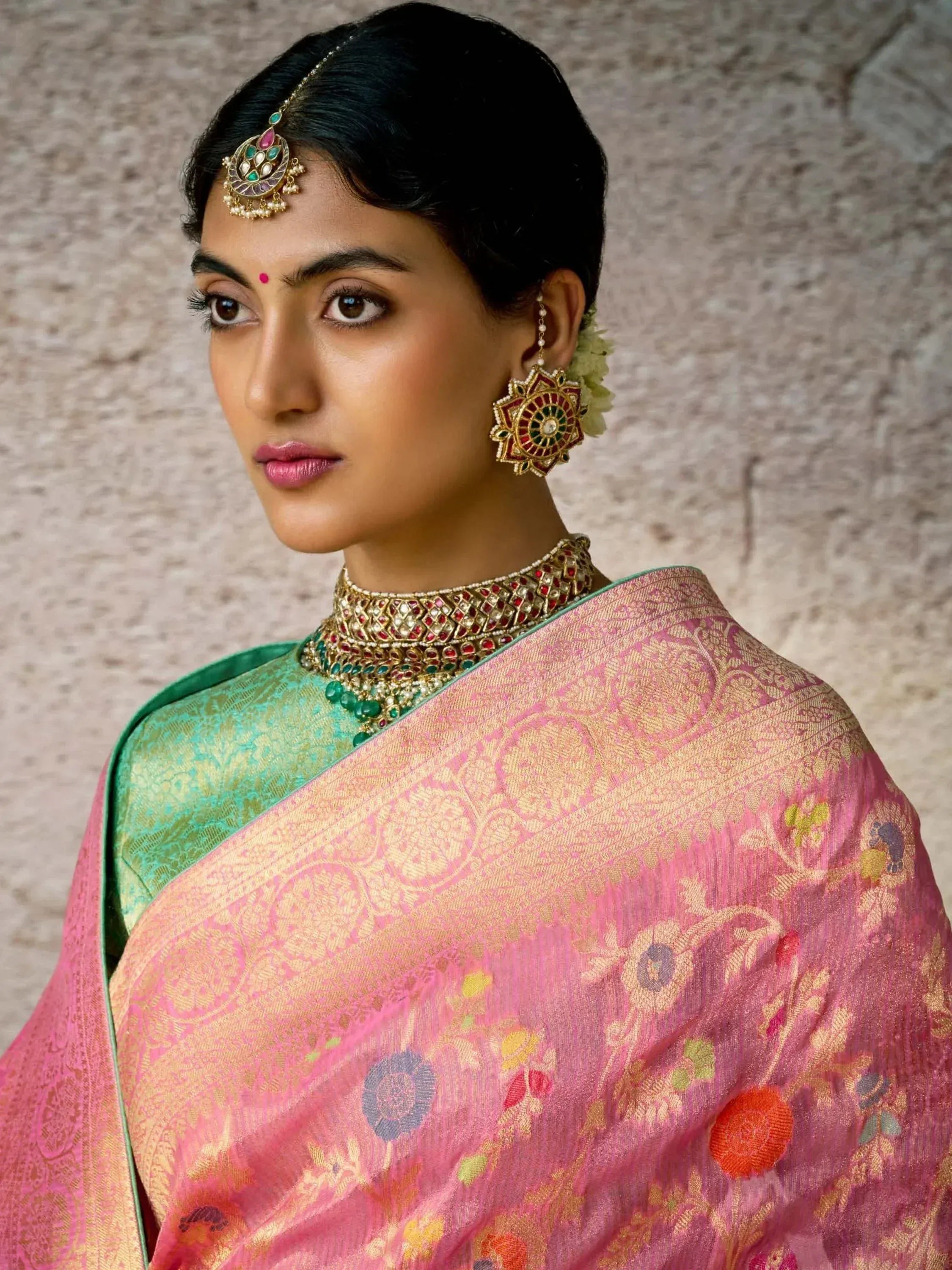 Woman in pink floral saree with green blouse, traditional Indian jewelry, and maang tikka for ethnic wear