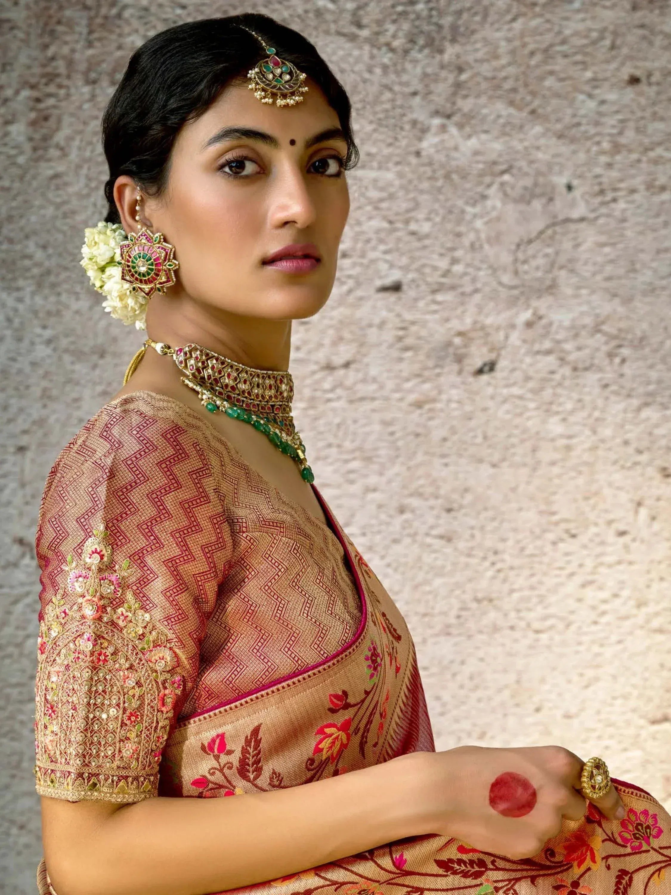 Woman in traditional Indian saree with intricate embroidery, temple jewelry, and floral hair accessory