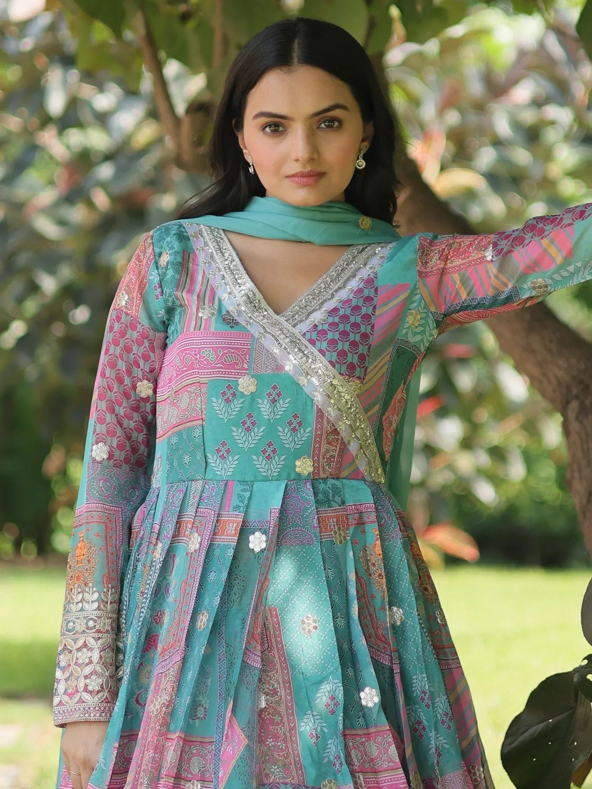 Woman in vibrant teal and pink printed ethnic gown with embroidery, styled with matching dupatta outdoors