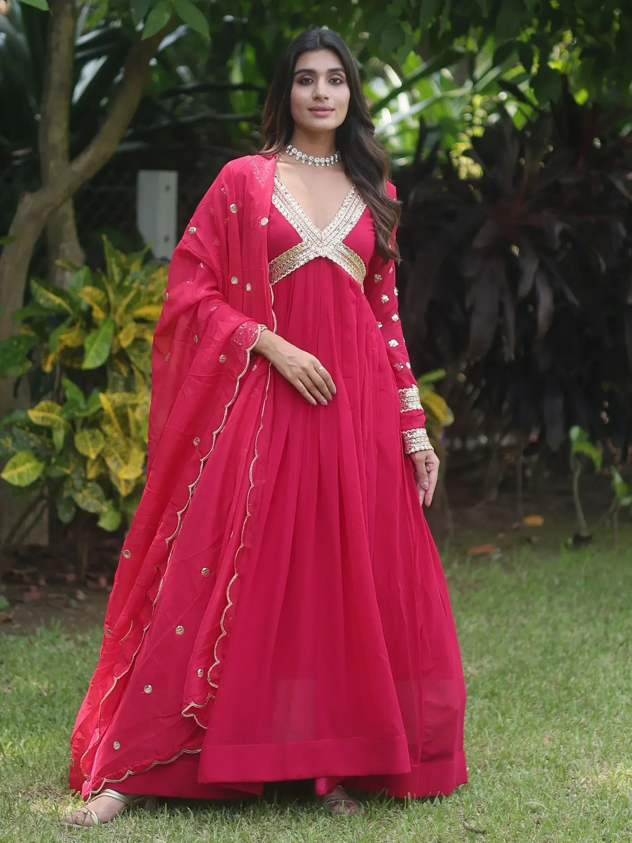 Woman in vibrant red ethnic gown with gold embroidery, perfect for Indian weddings or festive occasions