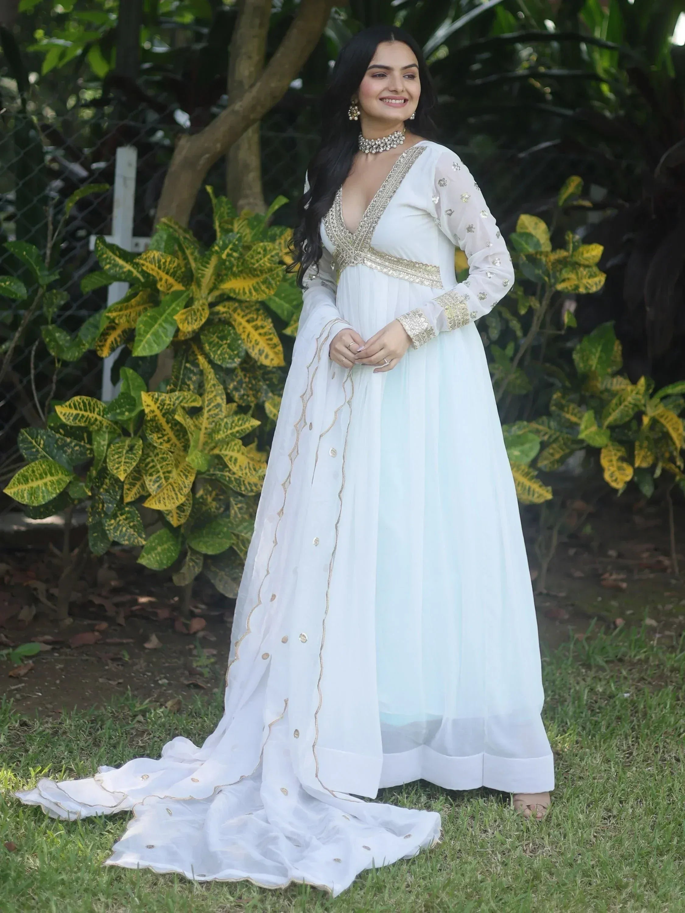White ethnic gown with gold embroidery, perfect for Indian weddings or festive occasions, styled with statement jewelry.