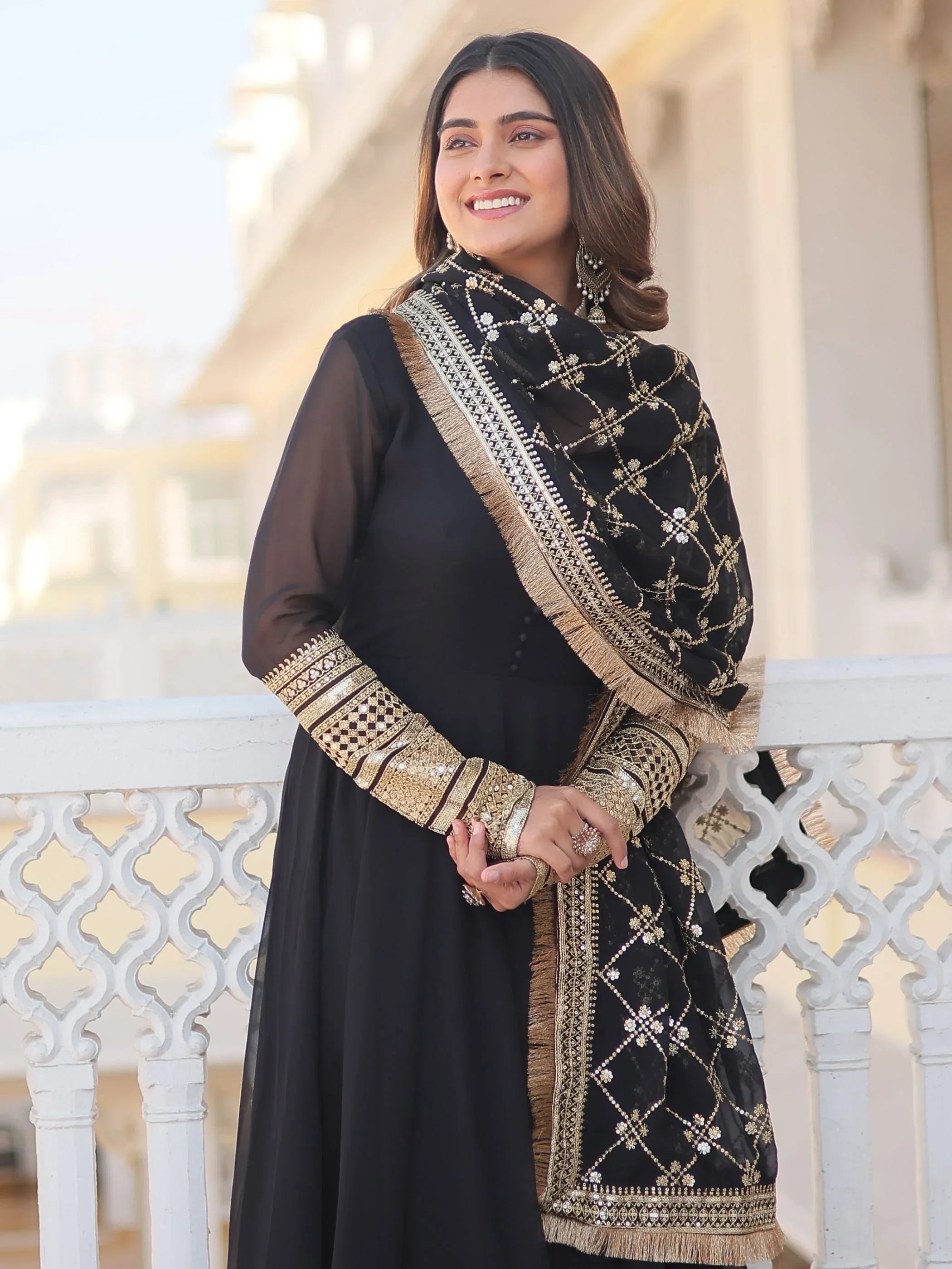 Woman wearing a black and gold embroidered ethnic gown with matching dupatta outdoors