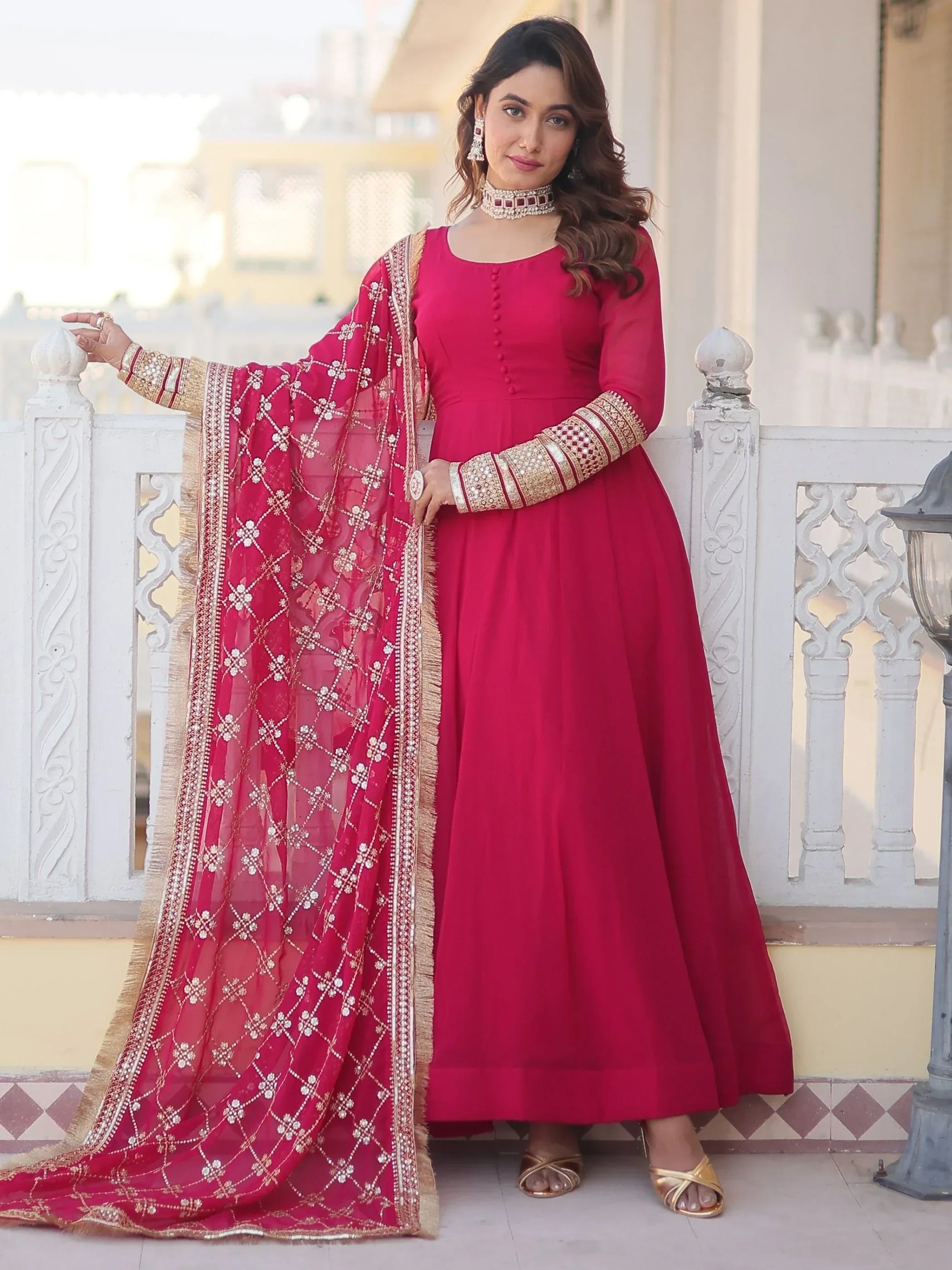 Woman in a pink ethnic gown with gold embroidered dupatta and traditional jewelry