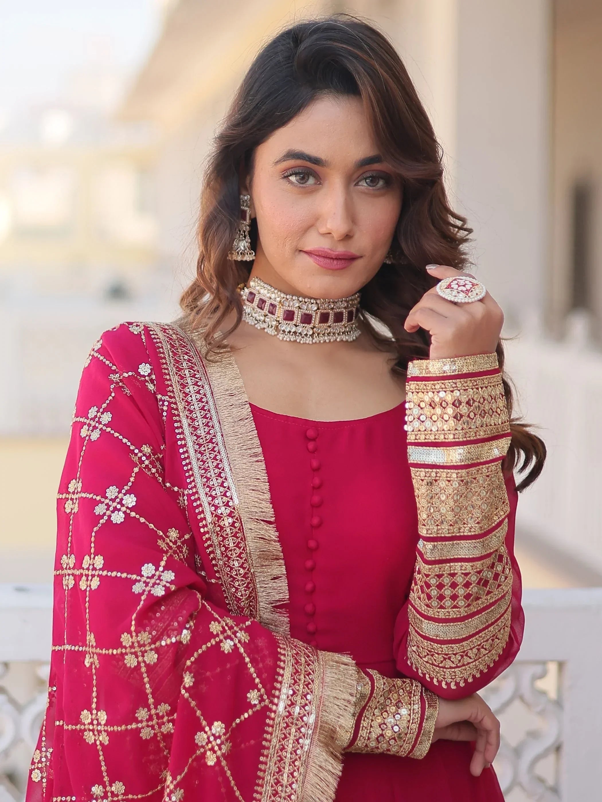 Woman in pink embroidered Indian ethnic gown with gold detailing and traditional jewelry
